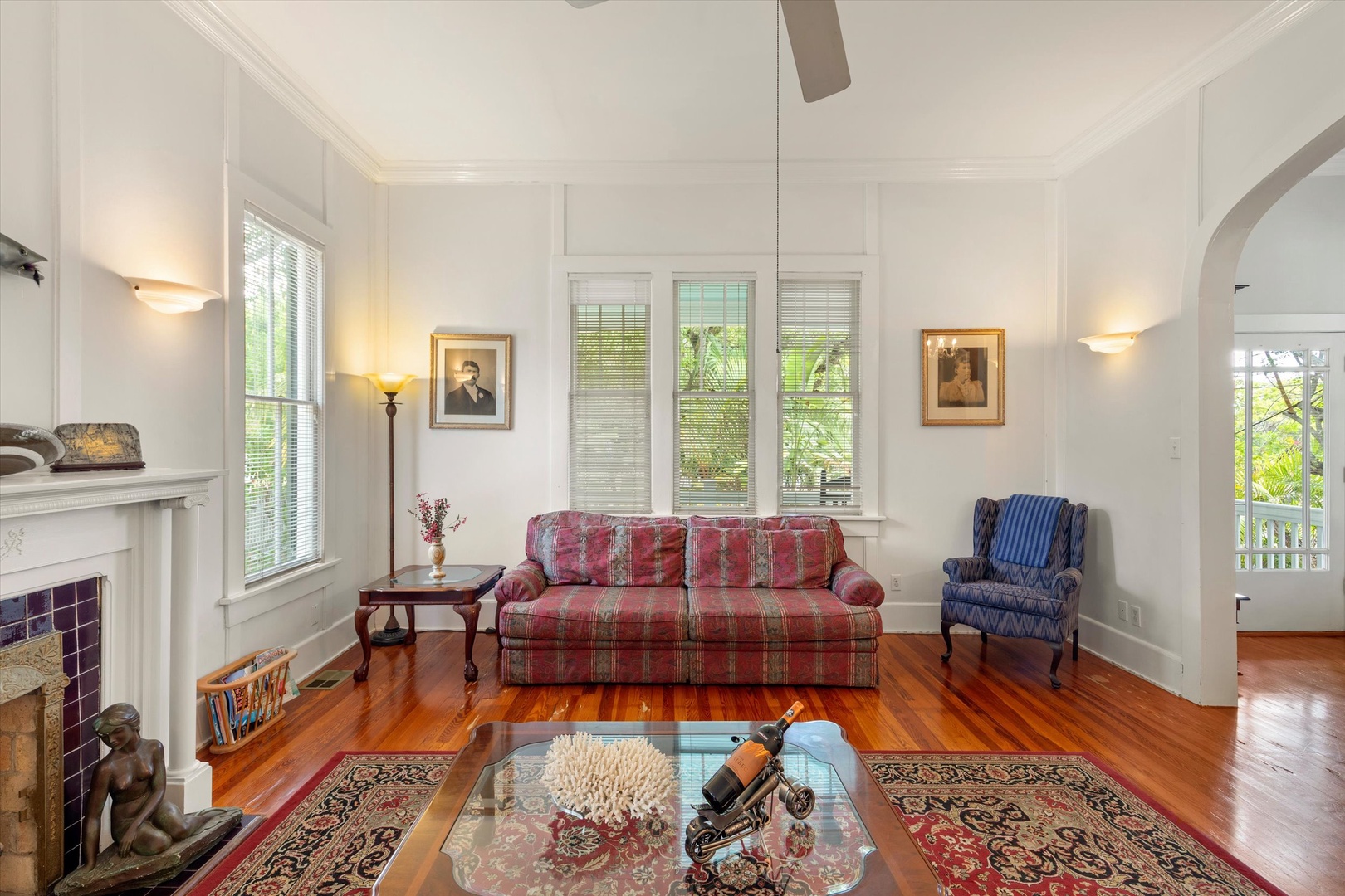 Unwind in your elegant living room with gleaming hardwood floors, vintage charm, and a cozy fireplace. High ceilings and natural light create a warm, inviting space.