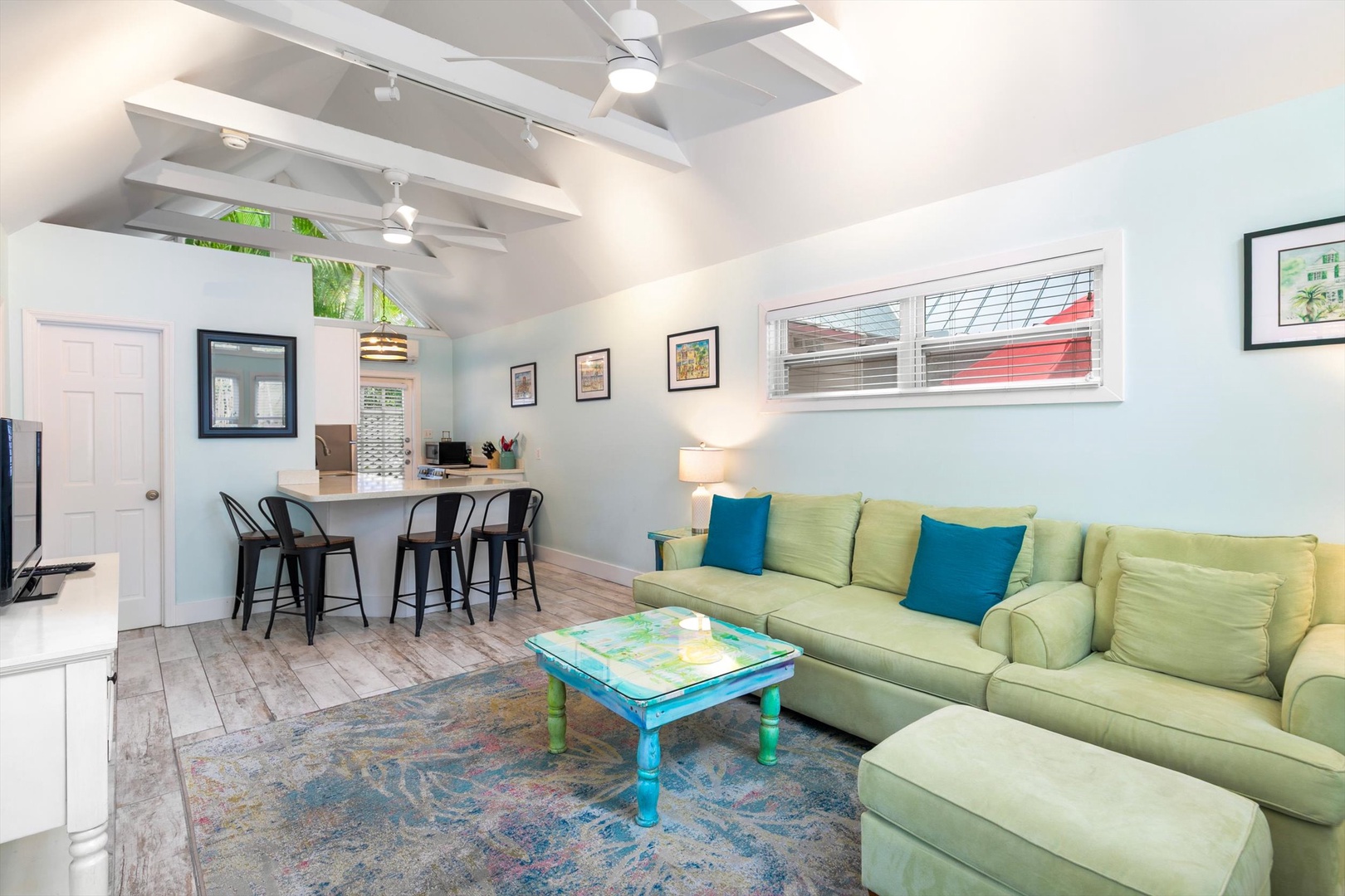 Relax into the inviting lime-green sectional in this bright, open living space with vaulted ceilings, coastal charm, and a colorful coffee table perfect for your morning brew.