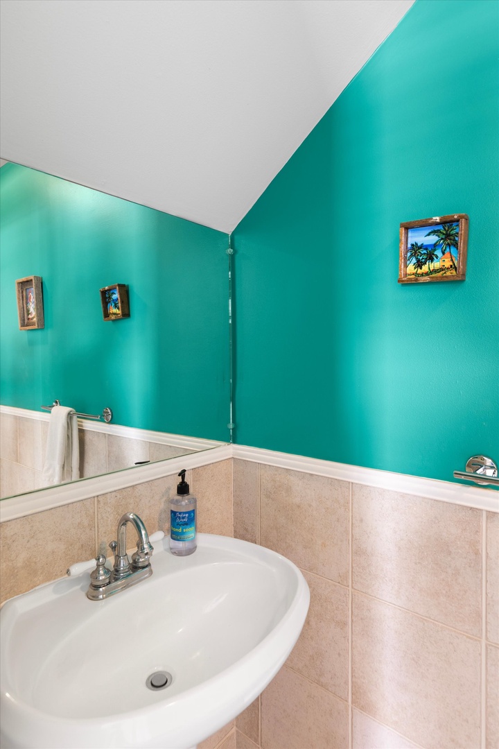 Step into your bright, cheerful bathroom with vibrant turquoise walls and beige tile accents. The spacious sink area and playful tropical touches create a refreshing start to your day.