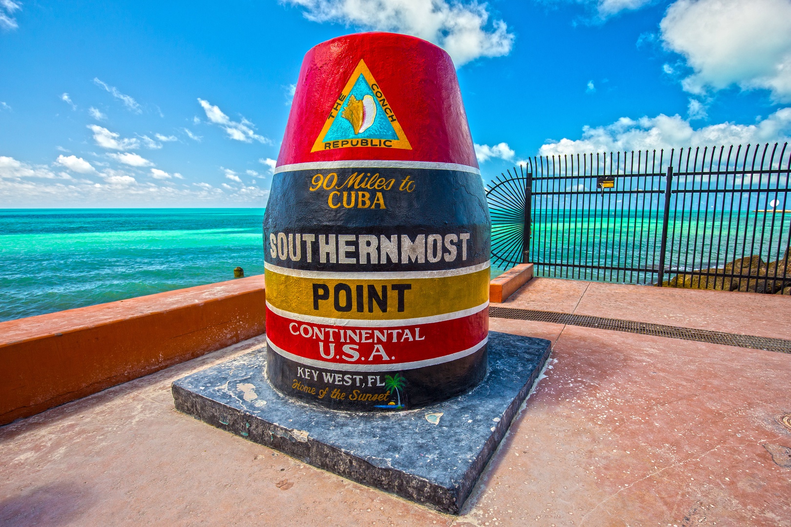 The iconic Southernmost Point marker stands as a colorful landmark in Key West, marking the edge of the continental United States with turquoise waters beyond.
