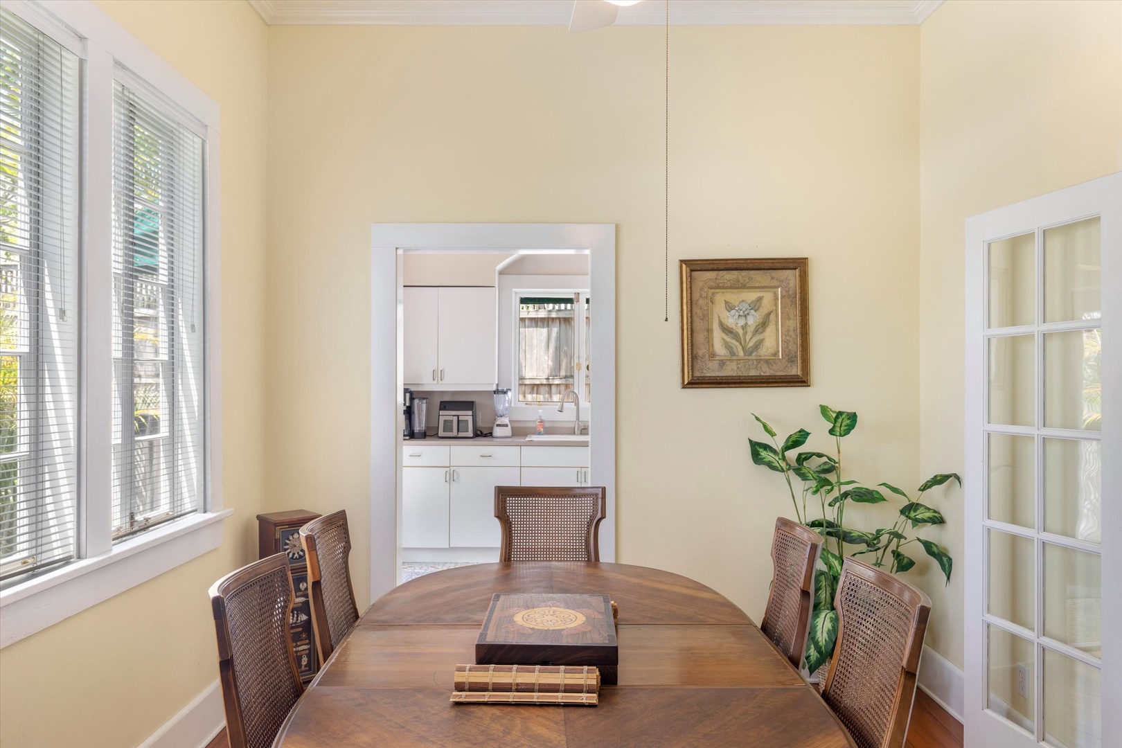 Step into your own bright and airy dining room with elegant cane-back chairs, beautiful natural light pouring through tall windows, and tasteful artwork that sets the perfect atmosphere for memorable meals with loved ones.