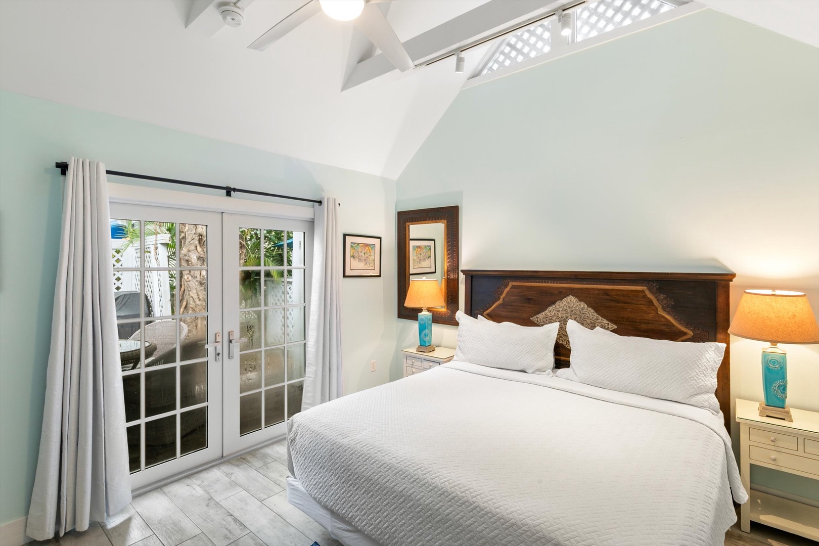 Step into this serene bedroom where soft coastal hues meet rustic warmth. Your private retreat opens to a charming outdoor space, bathed in natural light from vaulted ceilings above.