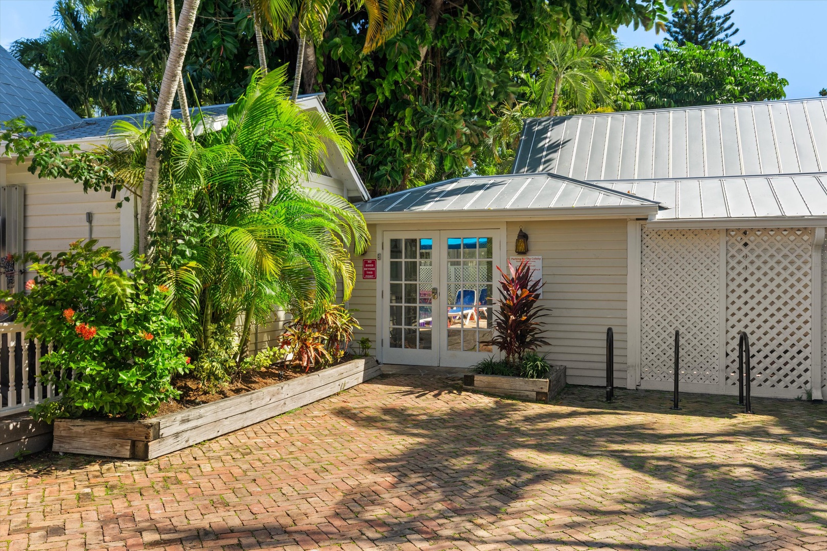 A charming tropical entrance surrounded by lush palms and vibrant greenery, offering easy access with ramps and ample parking on brick pavers, welcoming you to your island retreat.
