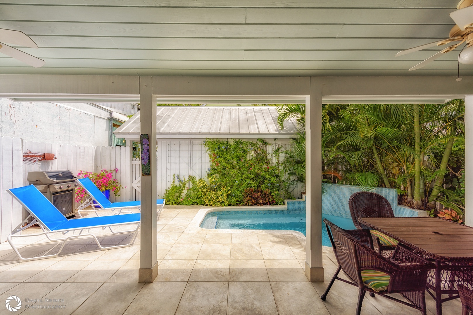 Private back patio with covered seating area, lounge chairs and pool
