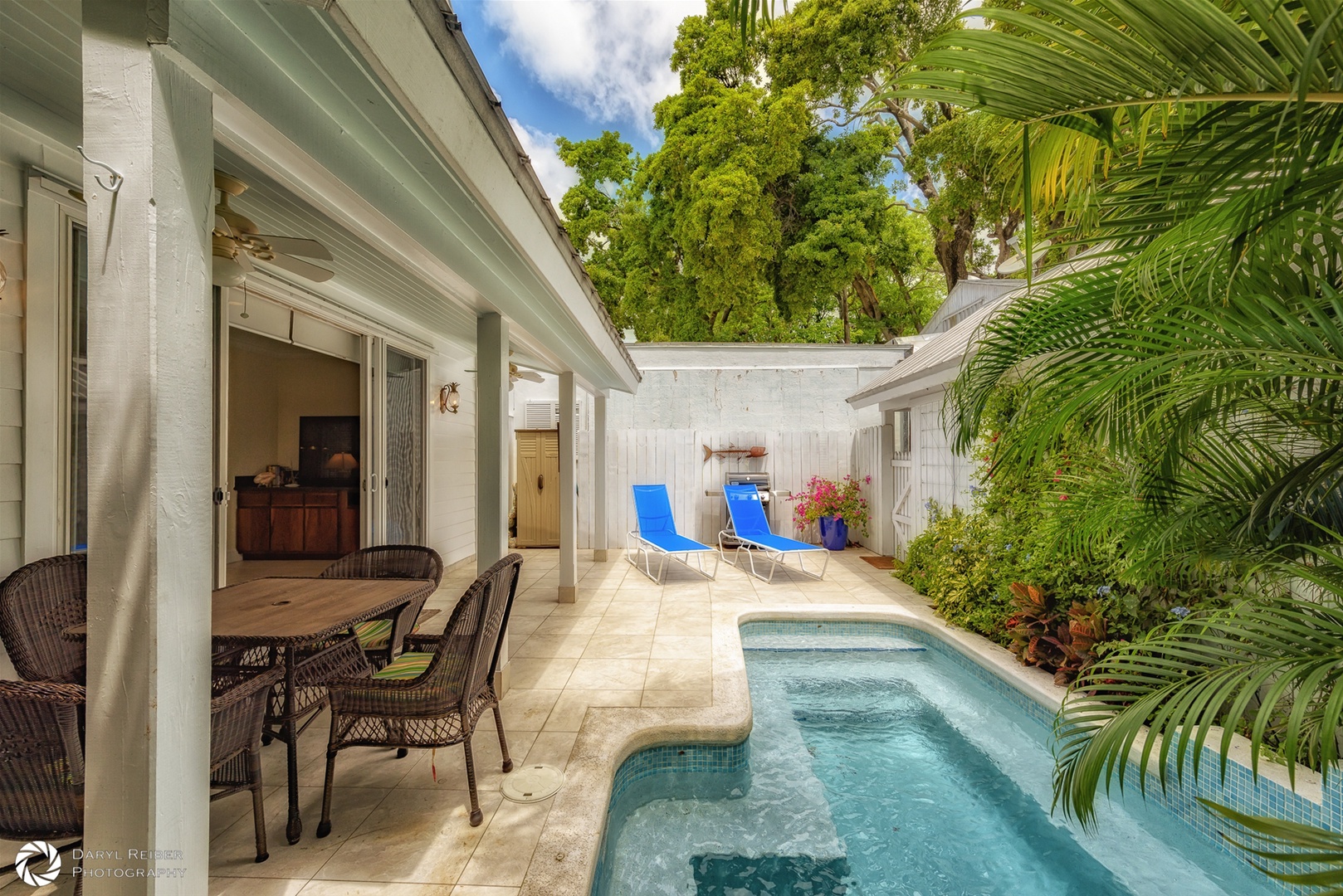Private back patio with covered seating area, lounge chairs and pool