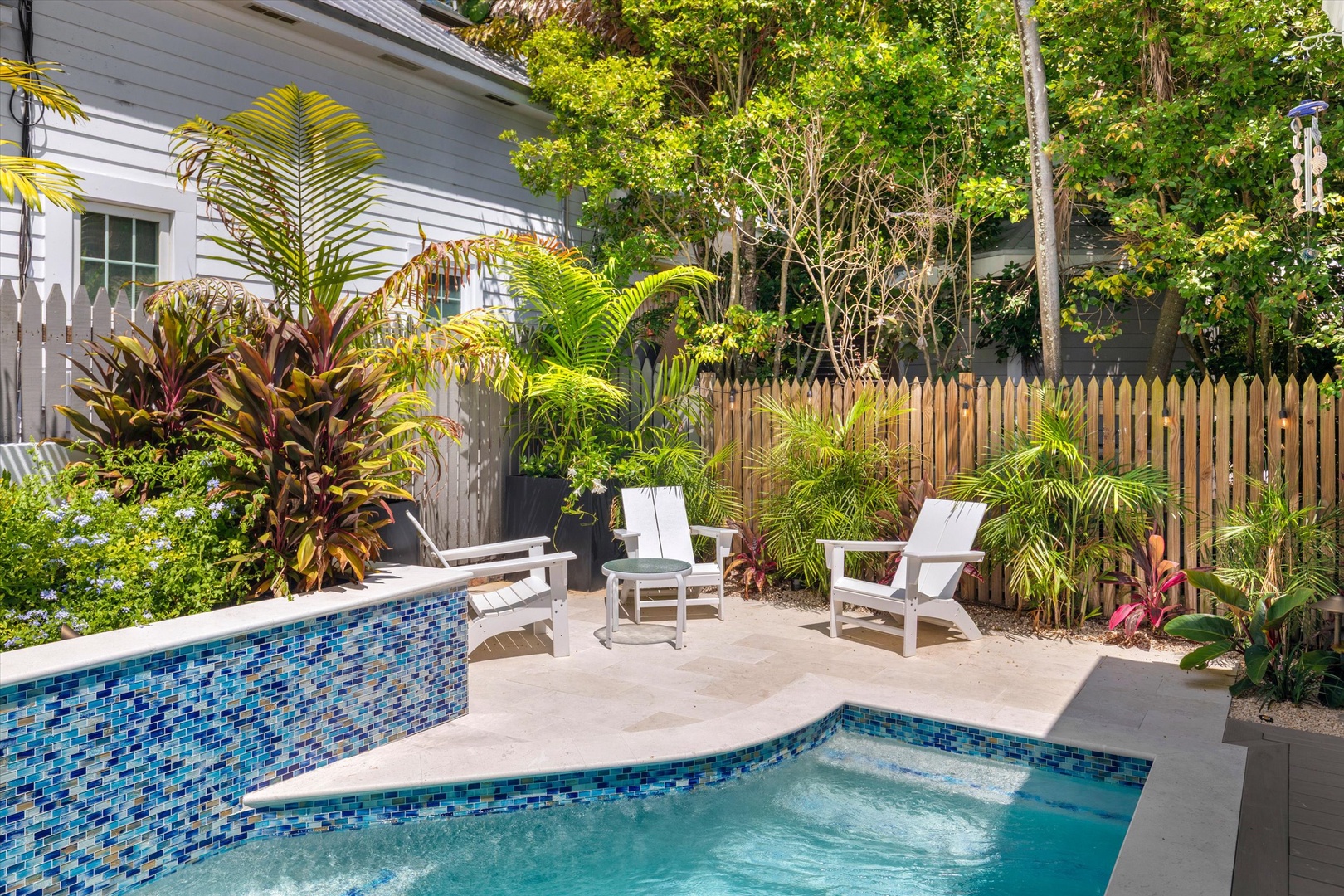 Slip into your private pool surrounded by lush tropical greenery and lounge on comfortable chairs—your serene backyard retreat awaits.