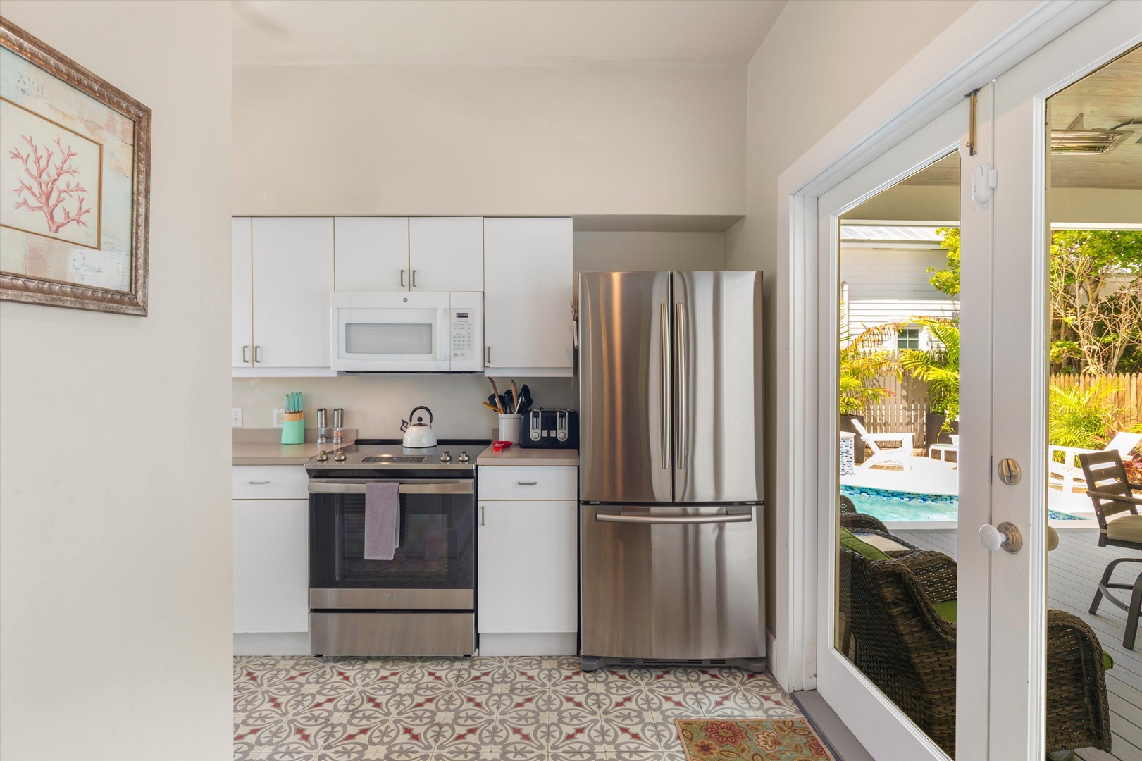 Your fully equipped kitchen features modern stainless steel appliances and opens to a sunny backyard where your private pool awaits—perfect for preparing breakfast before a refreshing morning swim.