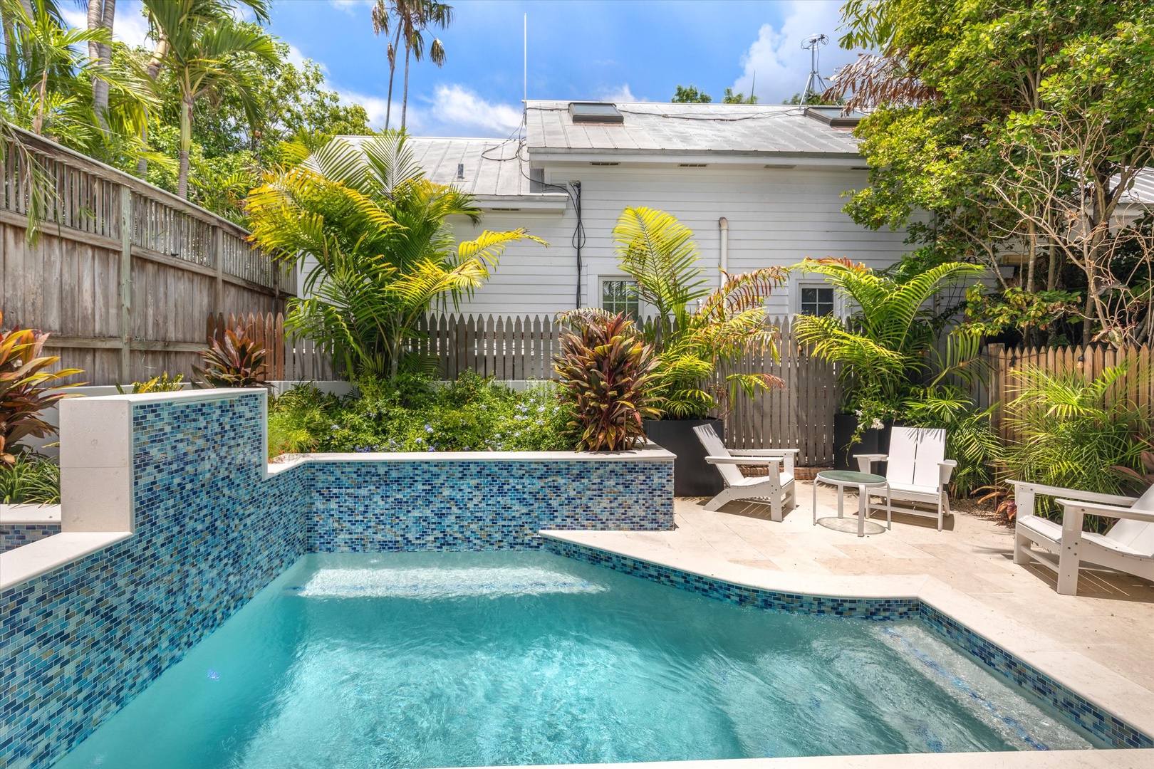 This private backyard oasis features a sparkling pool surrounded by lush tropical palms, offering a secluded escape perfect for your sunny getaway.