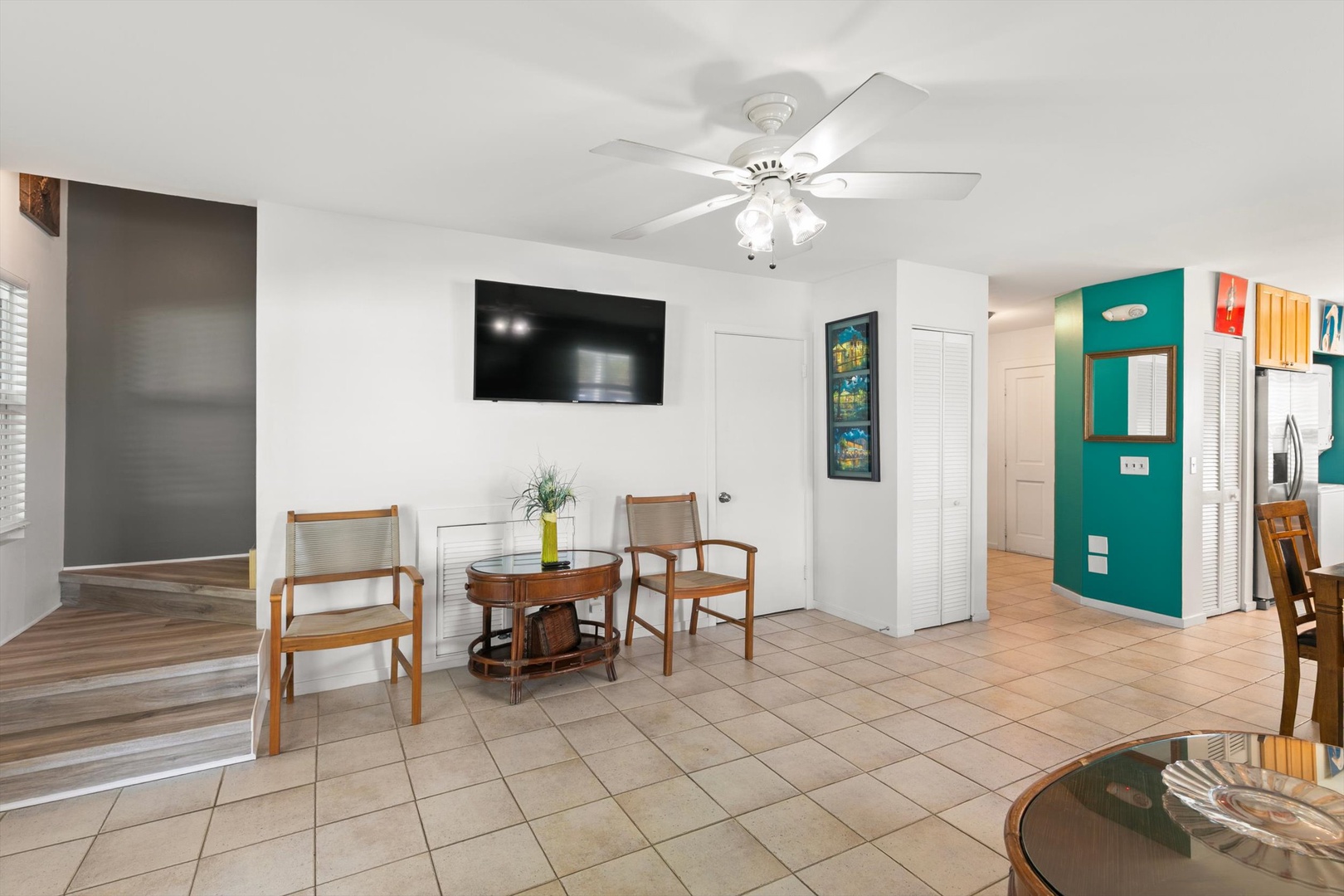Gather around the small café table in this open-plan living space, where cheerful pops of teal and sunny yellow add a playful touch. A ceiling fan keeps you cool while you unwind in this bright, casual retreat.
