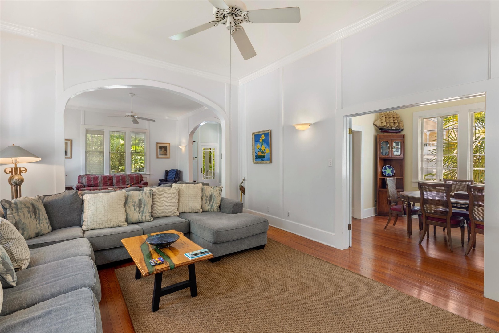 Relax in this bright, open living space where elegant arches and gleaming wood floors create a welcoming retreat. Sink into plush seating under ceiling fans that keep you cool and comfortable year-round.