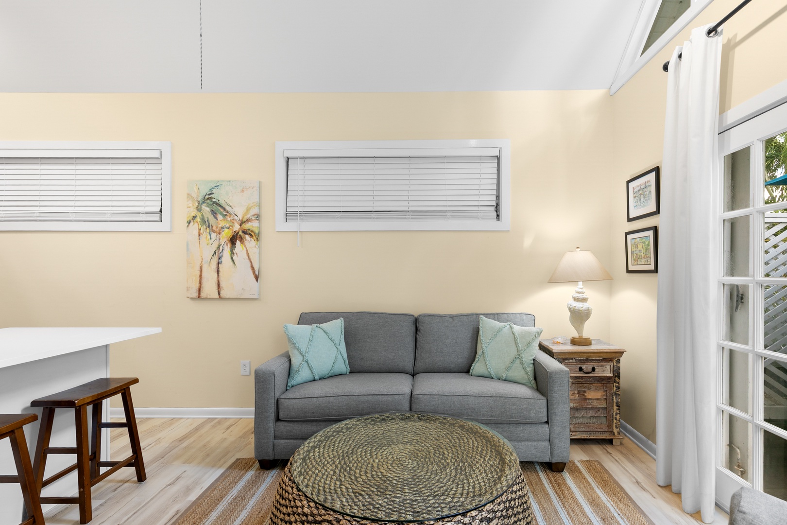 Unwind in your cozy living area with a comfy sofa, calming coastal touches, and natural light filtering through the windows to create a serene, beachy atmosphere.
