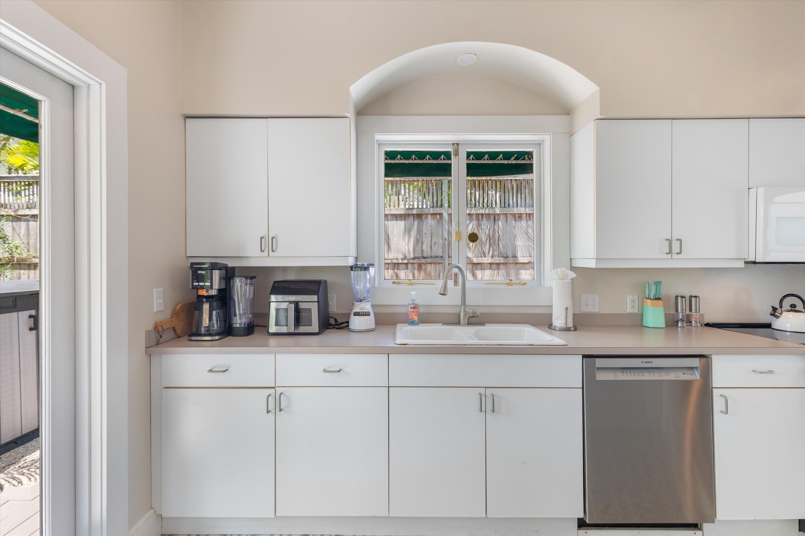 Your bright, fully-equipped kitchen features stainless steel appliances, ample cabinet space, and a charming arched window letting in natural light to inspire your cooking adventures.