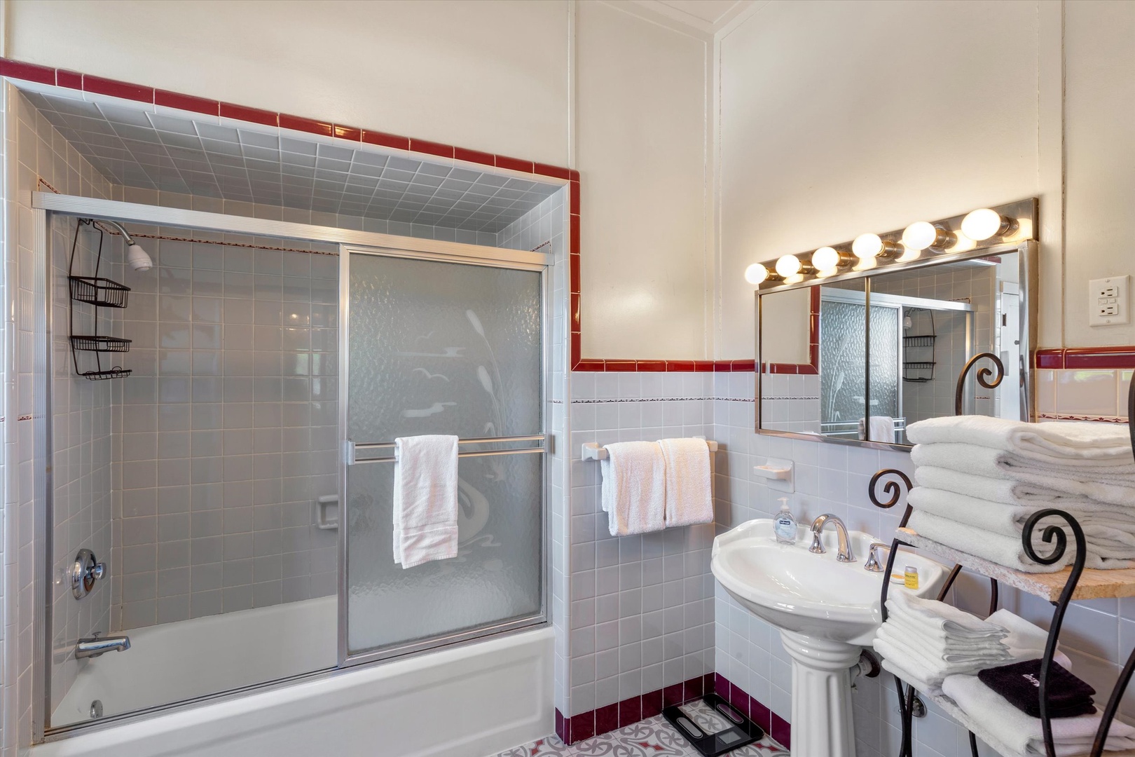 A beautifully tiled bathroom awaits with a tub-shower combo, fluffy towels, and Hollywood-style lighting to brighten your morning routine.