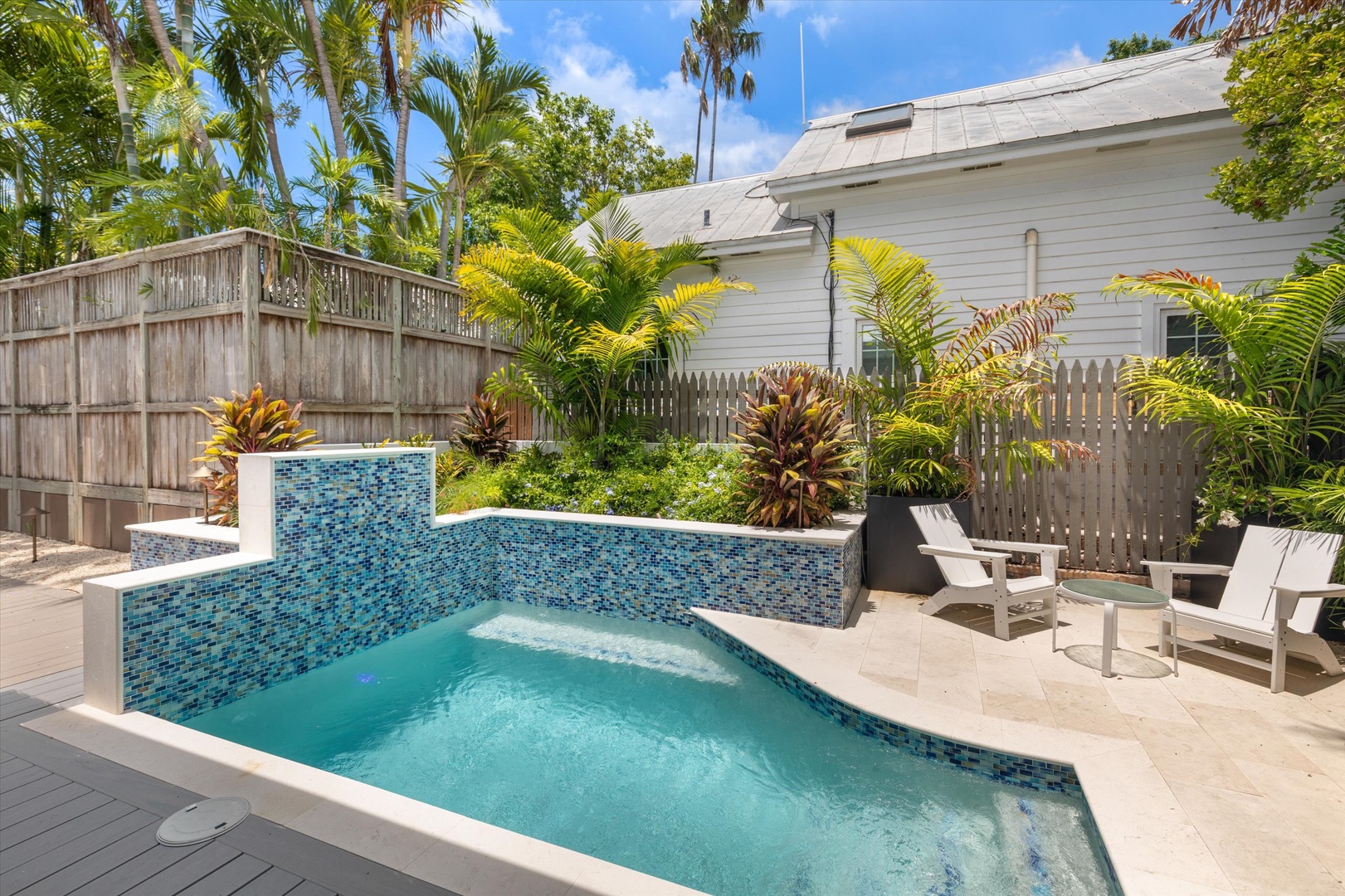 Private pool with mosaic tile design and a cascading water feature, surrounded by tropical palms and lounge chairs—your personal oasis for sun-soaked relaxation.