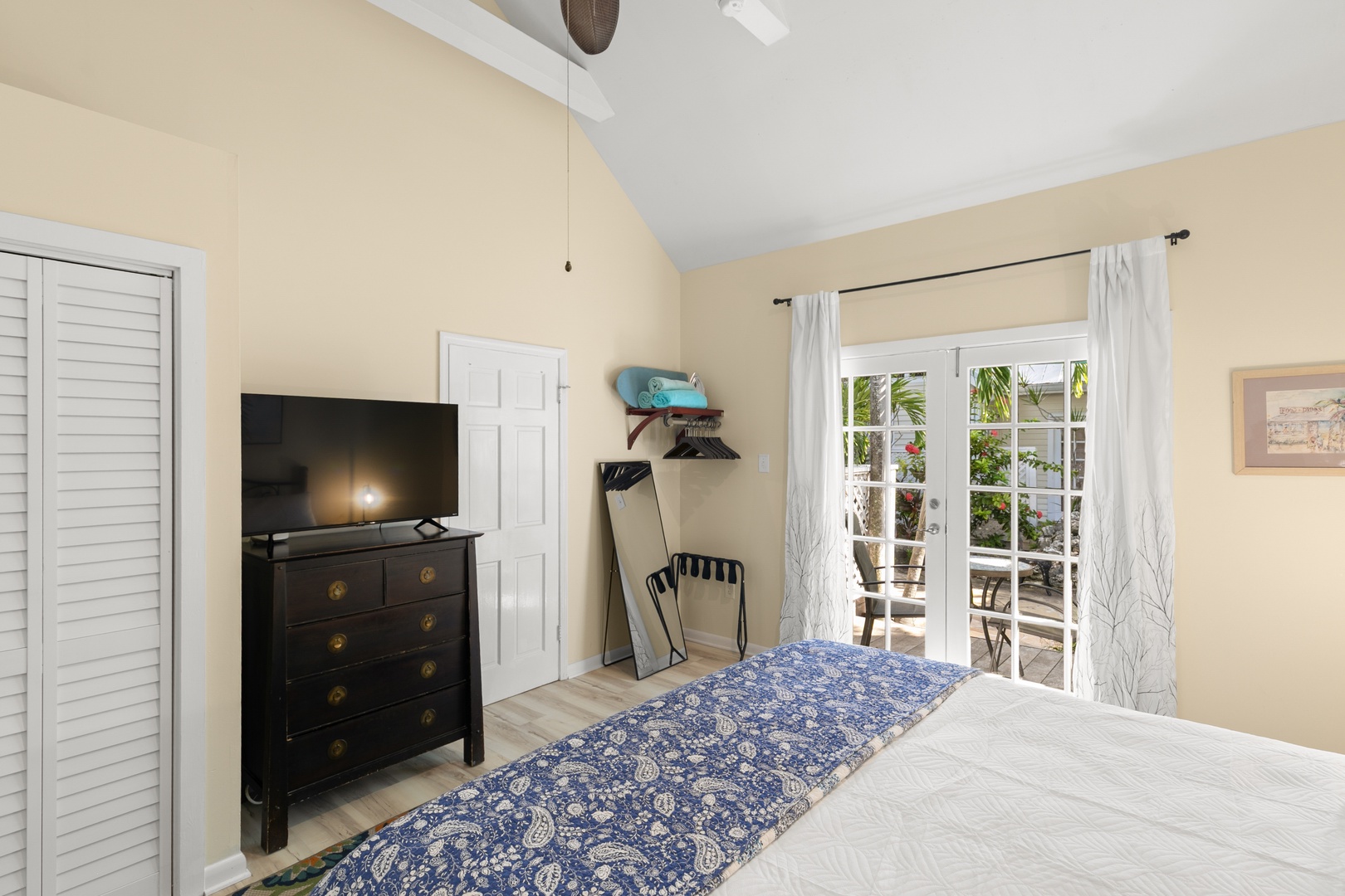 Your bright, airy bedroom opens directly onto the terrace through elegant French doors, inviting natural light and tropical breezes. The vaulted ceiling and coastal decor create a serene retreat perfect for unwinding after island adventures.