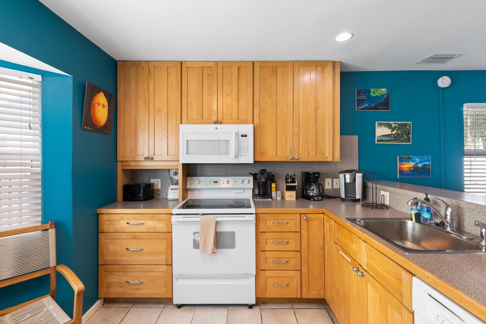 Your fully equipped kitchen awaits, with warm wood cabinetry and cheerful turquoise walls, everything you need to whip up a home-cooked meal or morning coffee.