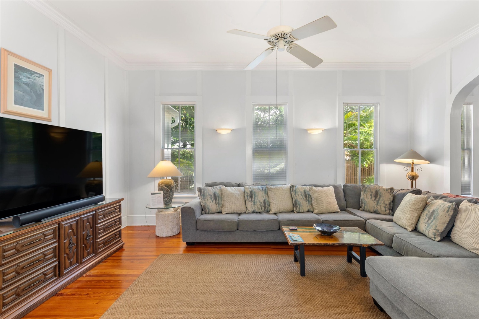 Settle into your spacious living room, where natural light pours through tall windows and a ceiling fan keeps you cool. The sectional invites long conversations or movie nights.