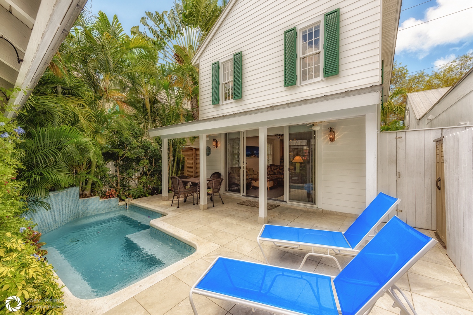 Private back patio with covered seating area, lounge chairs and pool