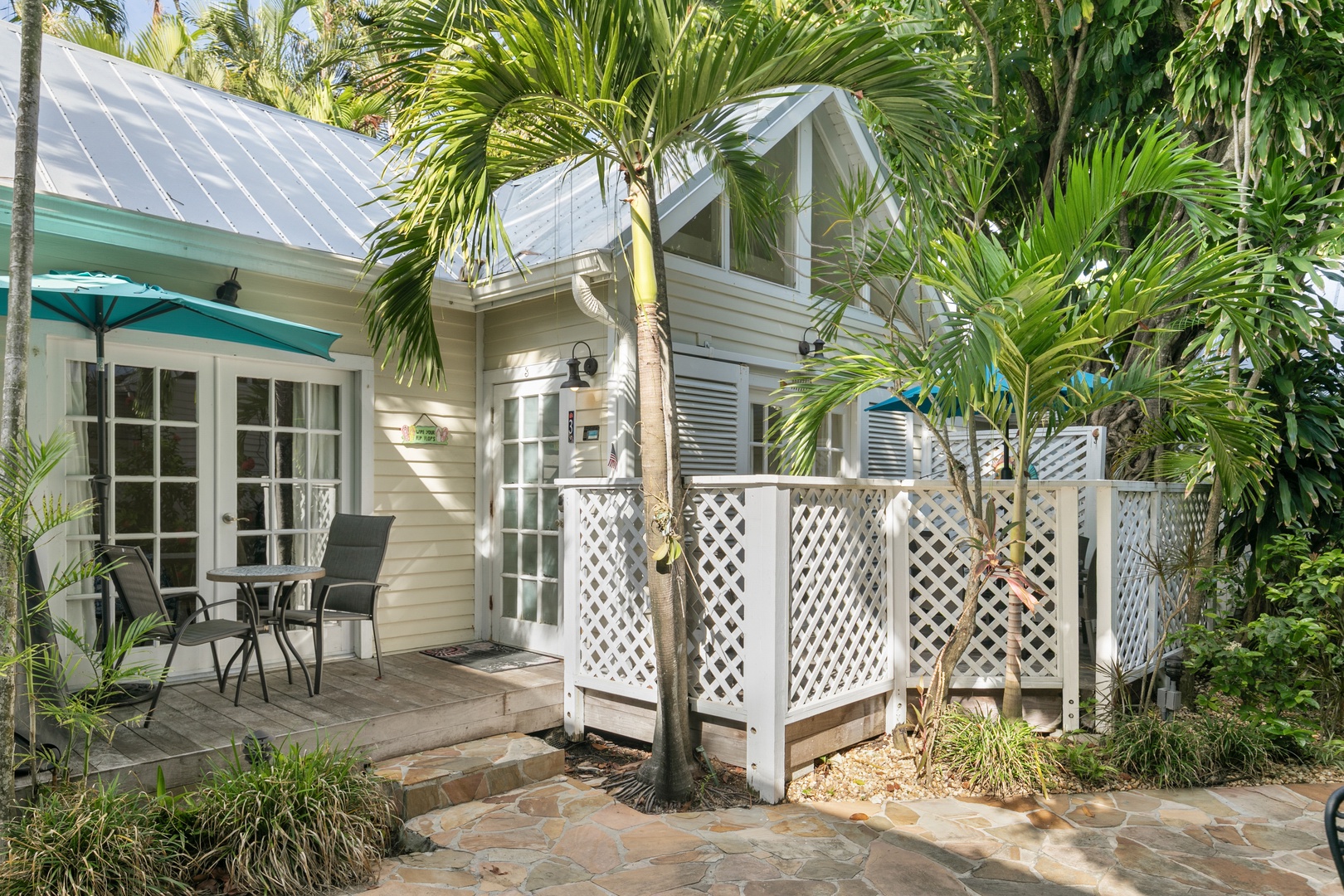 A charming tropical cottage surrounded by lush palms, offering your own peaceful outdoor retreat with cozy patio seating.