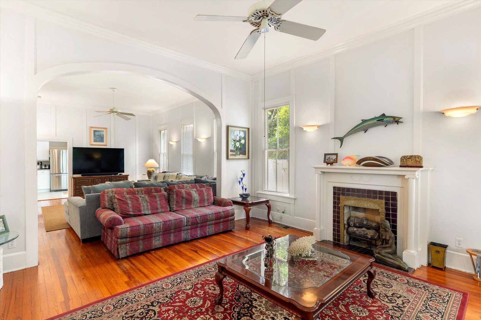 Settle into comfort in this bright living space with gleaming hardwood floors, cozy fireplace, and ceiling fan for year-round relaxation.