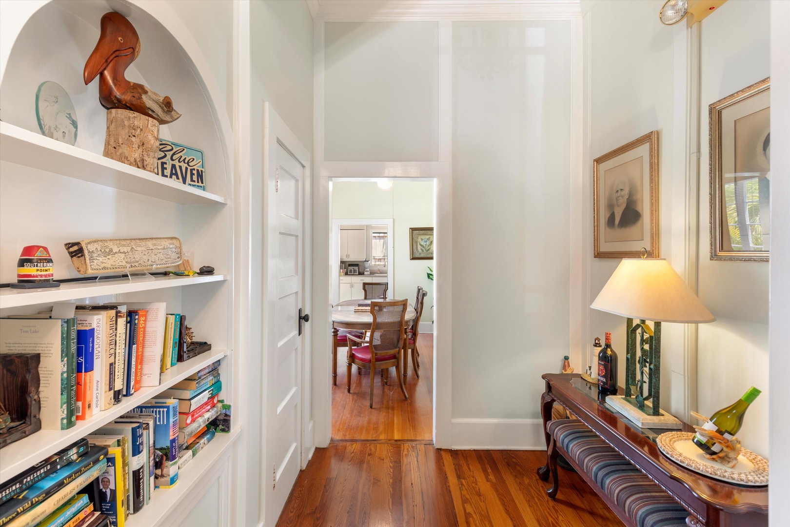 Step into a bright hallway adorned with curated books, artwork, and warm wooden floors that lead you to inviting spaces beyond.