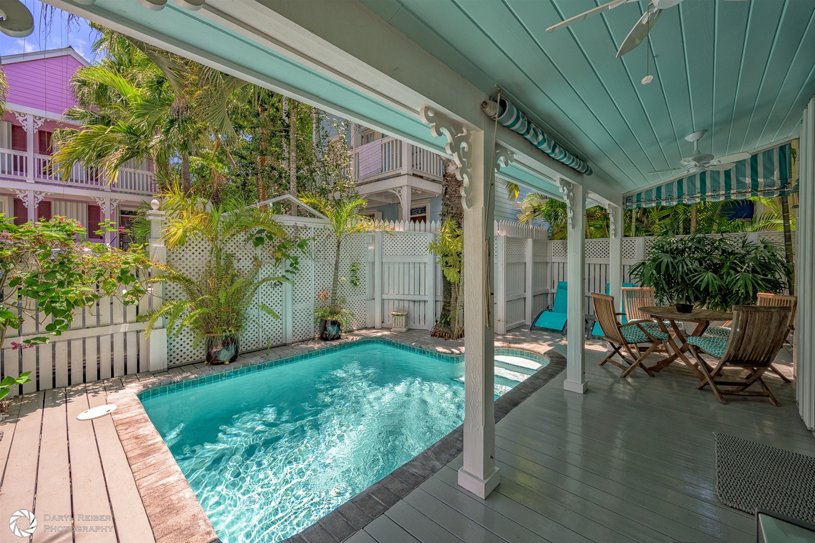 Private covered patio with seating area, pool and lounge chairs