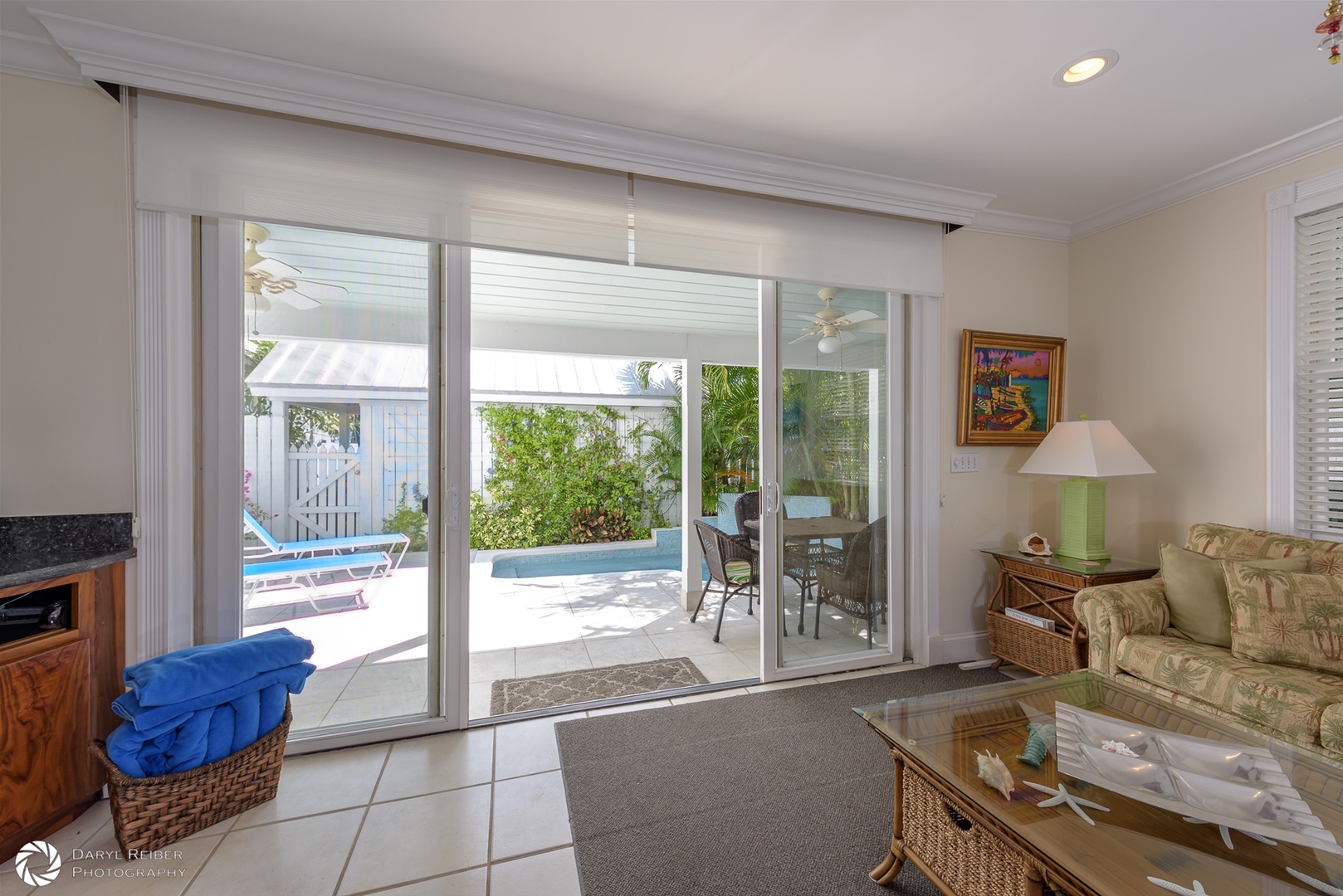 Doors in living room to private patio with pool, covered seating area and lounge chairs