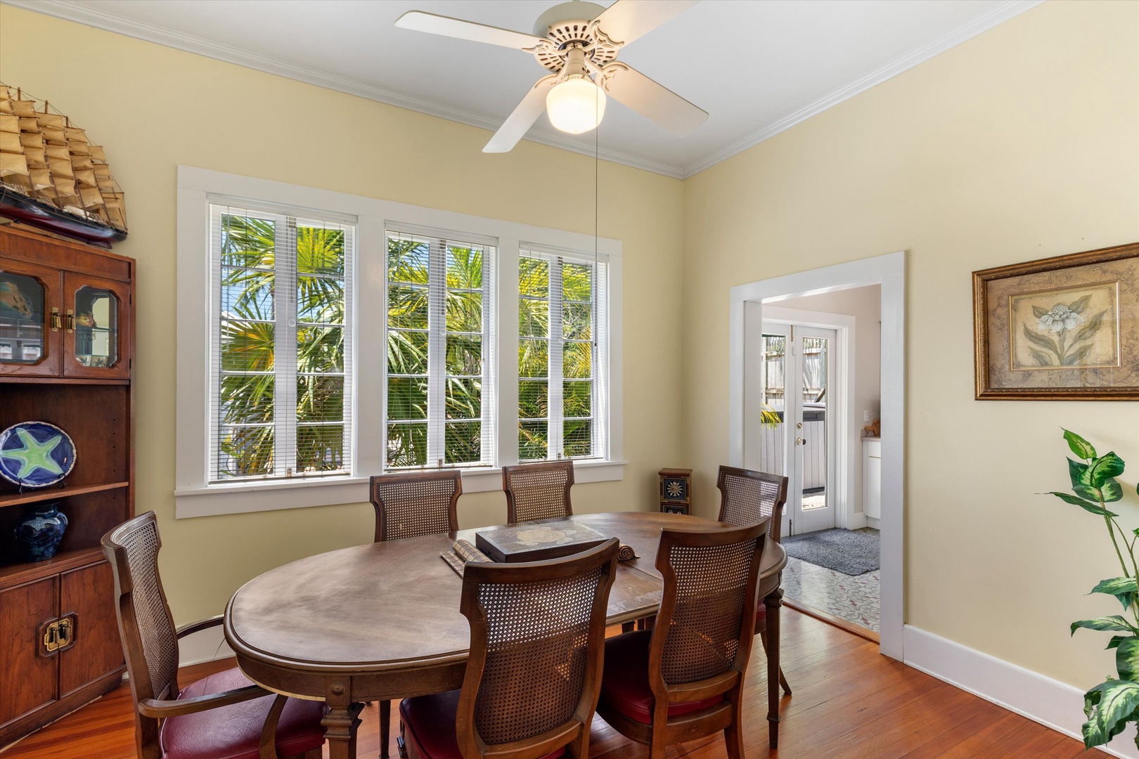 Gather around this beautiful dining table for meals together, enjoying natural light from the windows and a ceiling fan overhead. The classic wooden furniture and warm tones create an inviting atmosphere for your stay.
