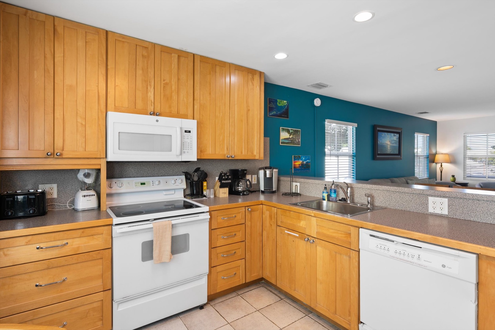 Your fully equipped kitchen awaits, with warm wood cabinetry and cheerful turquoise walls, everything you need to whip up a home-cooked meal or morning coffee.