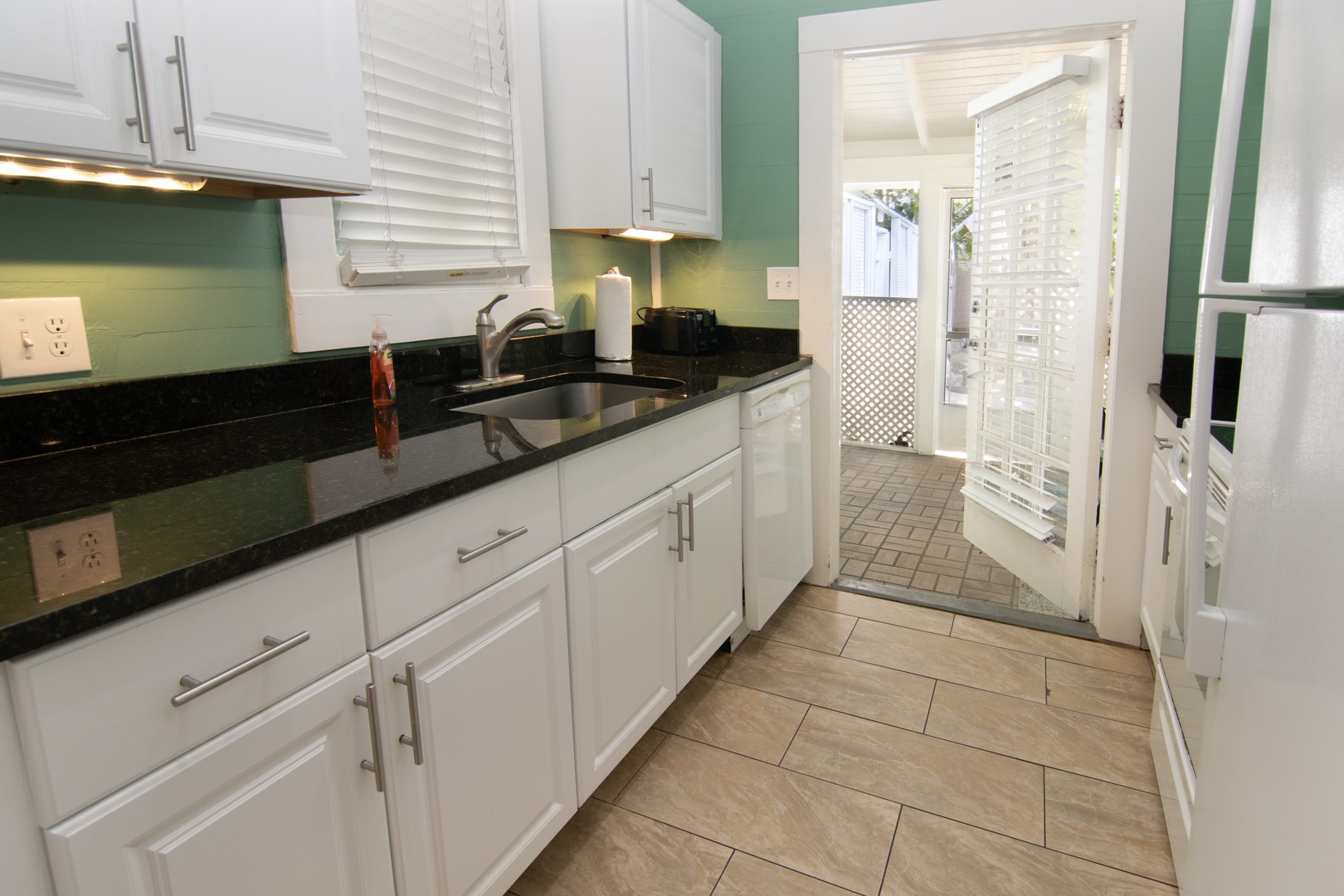 Kitchen with back door that opens up to a private screened in covered patio with seating
