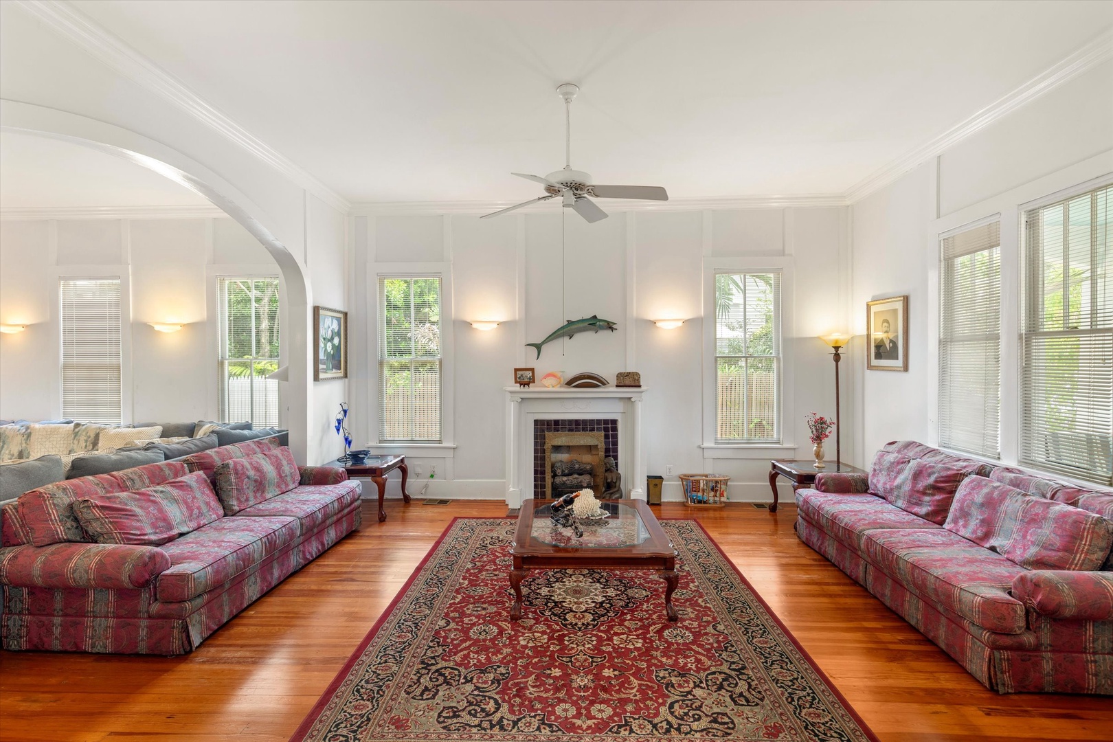 Settle into this bright, spacious living room where elegant crown molding and warm hardwood floors greet you. Gather around the fireplace or relax on plush seating as natural light fills your home away from home.