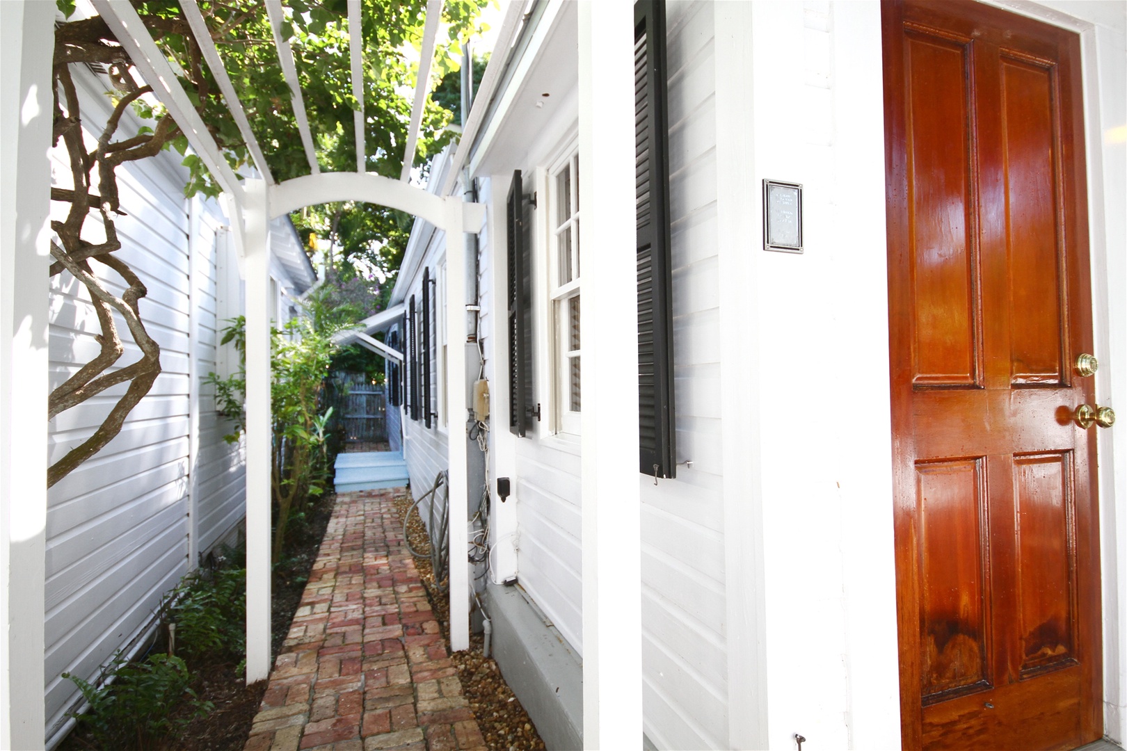Side walkway to fenced in back yard with deck and seating area