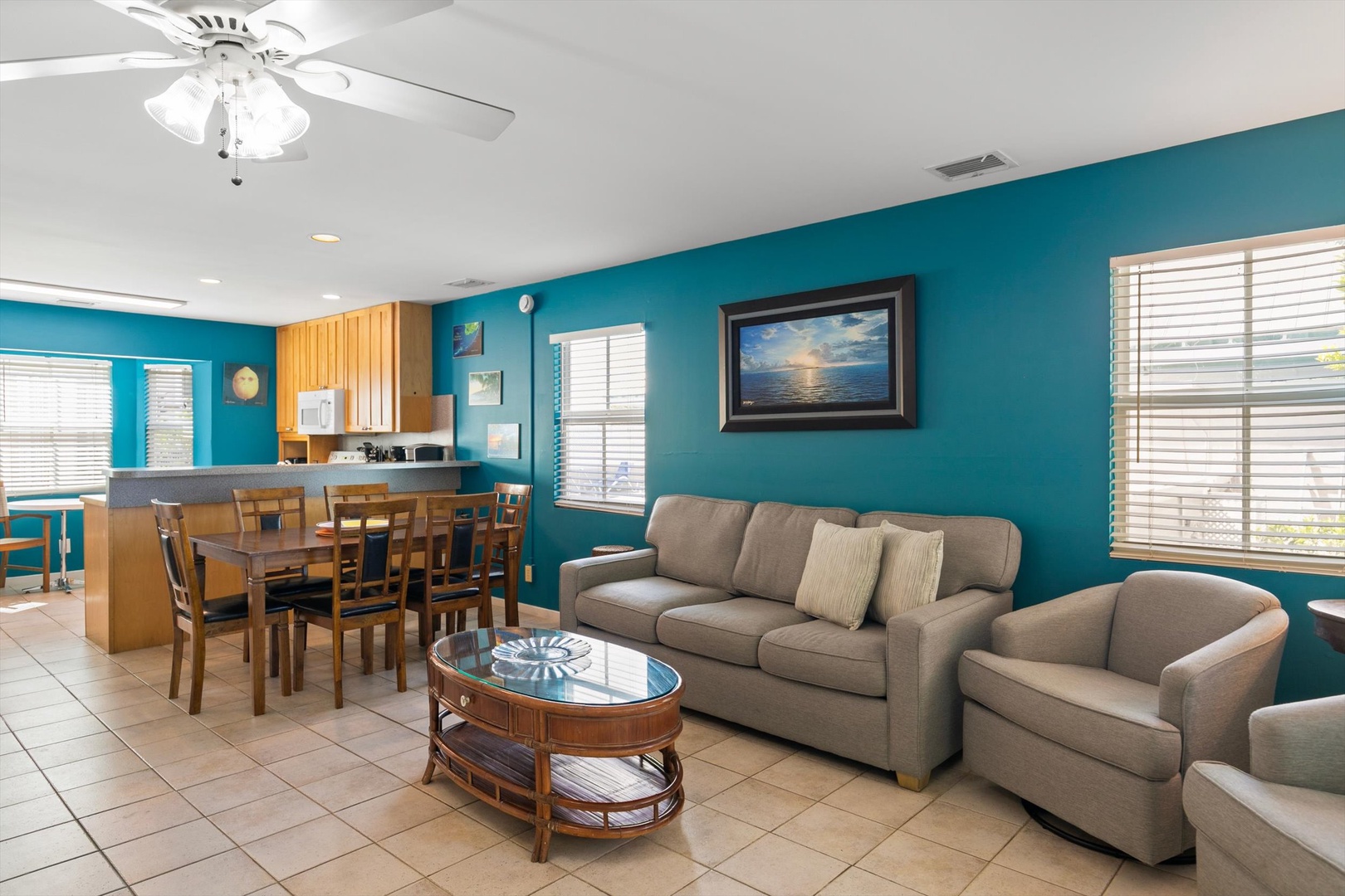 Settle into your comfortable living space, where bold turquoise walls and soft neutral furnishings create an inviting retreat. Gather at the dining table for meals together or sink into the cozy couch and unwind after your beach adventures.