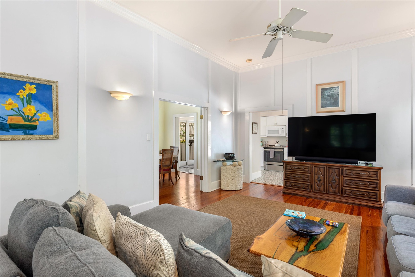 Relax in your bright, airy living room with plush seating, a large TV for movie nights, and warm wood floors that connect seamlessly to the kitchen.