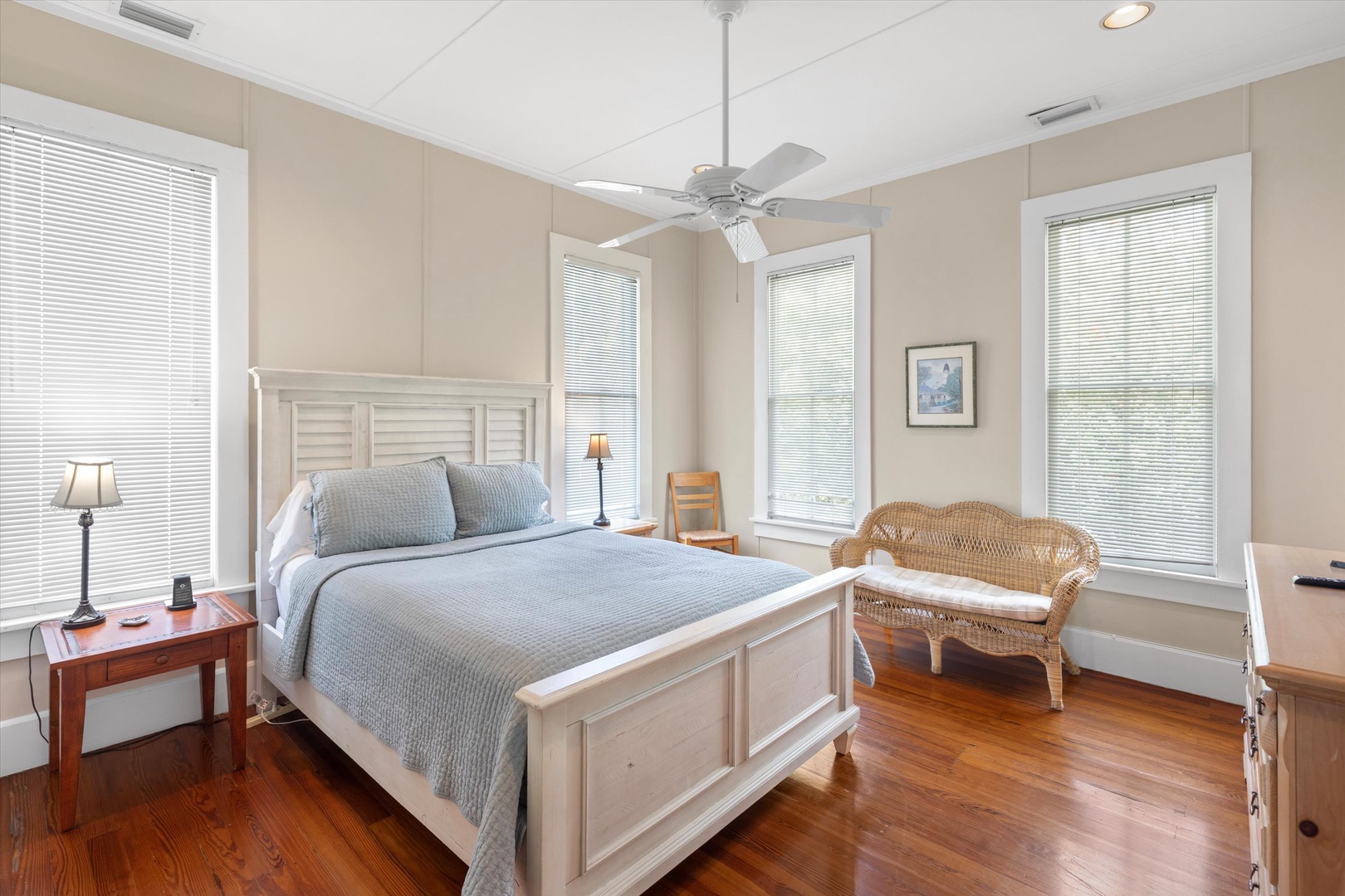 Step into your serene guest bedroom where natural light floods through tall windows and gentle ceiling fans keep the air fresh. Sink into plush bedding and unwind in the cozy wicker loveseat after a day of adventures.