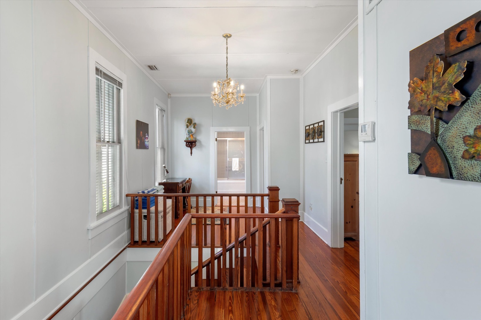 An elegant hallway with gleaming hardwood floors, classic chandelier lighting, and charming artwork creates a welcoming transition space as you move through your retreat.