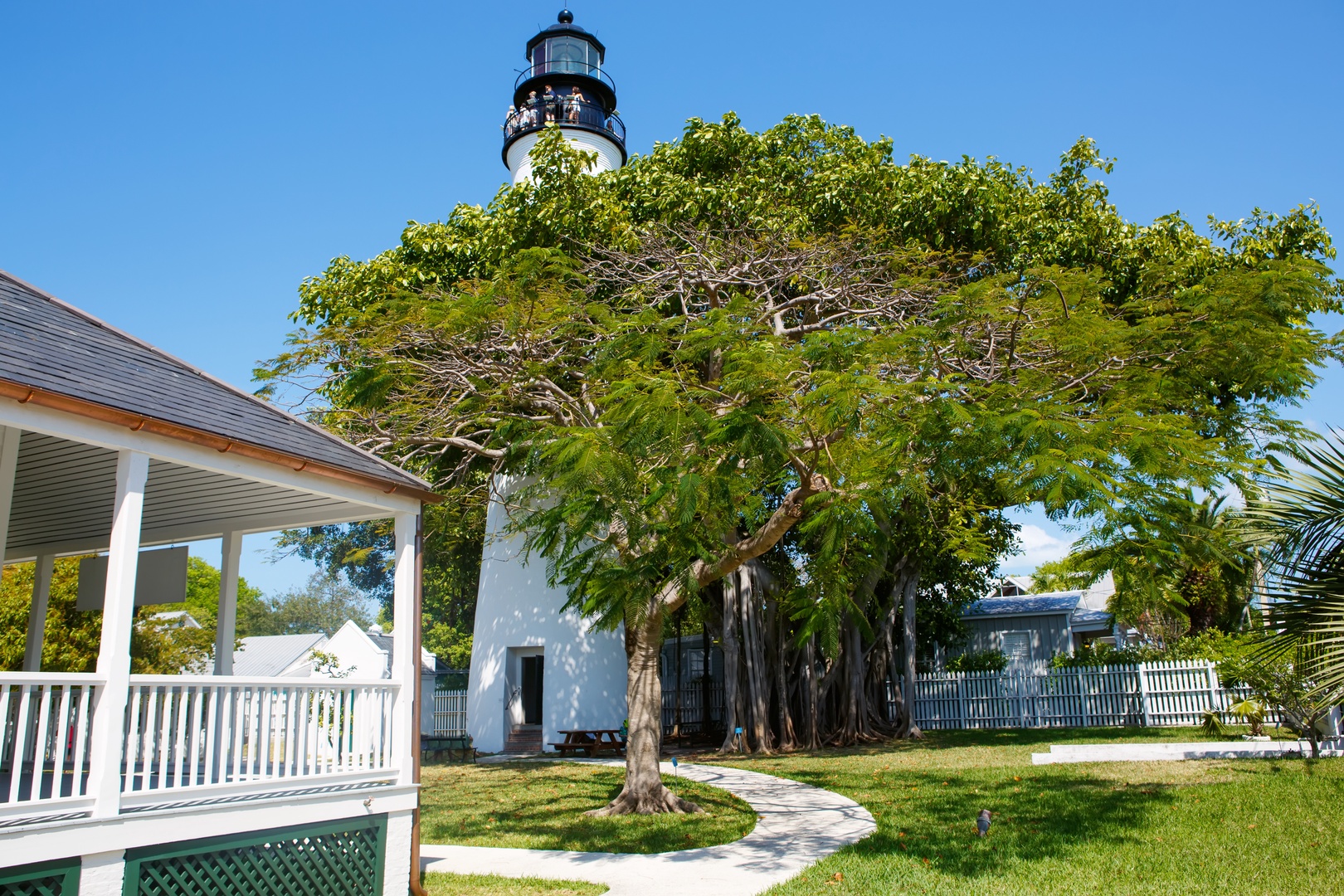 This historic lighthouse stands as a notable landmark near the property, surrounded by lush tropical trees and manicured grounds in a charming residential neighborhood.