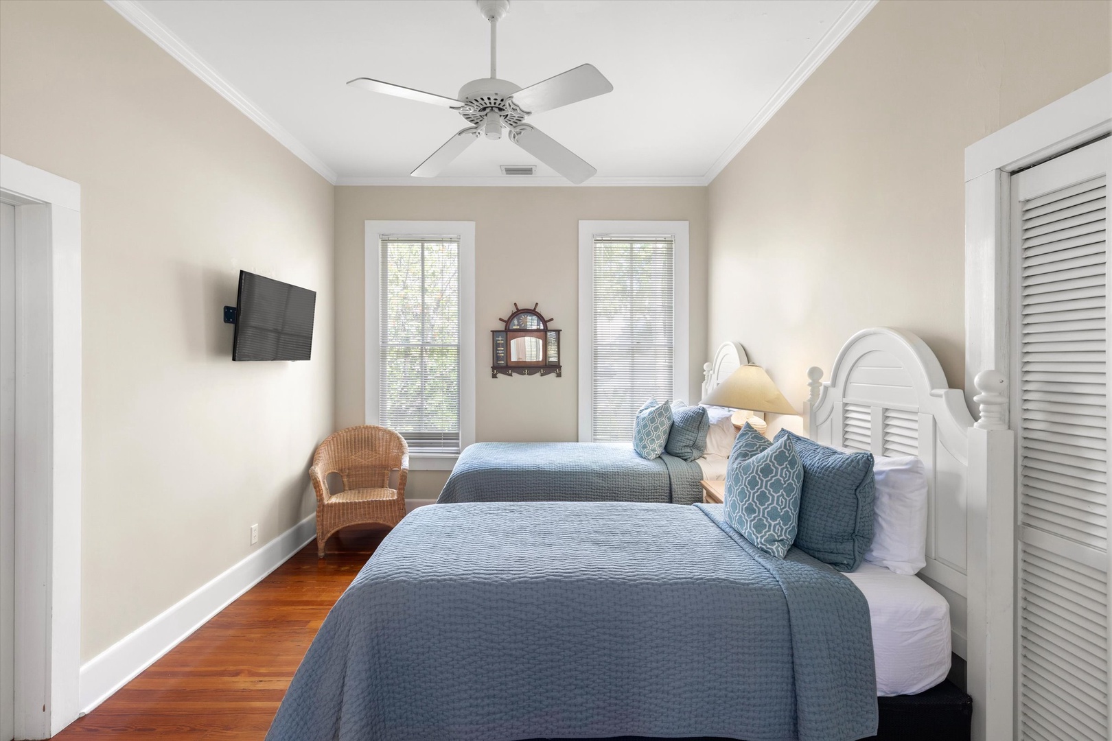 Unwind in this serene bedroom with two cozy beds, warm hardwood floors, and a gentle ceiling fan. Large windows flood the space with natural light, creating a peaceful retreat for your stay.