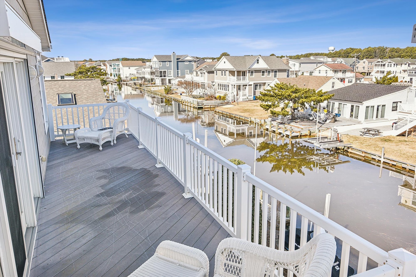Spacious waterfront deck overlooking a peaceful canal and charming coastal neighborhood, featuring comfortable seating perfect for morning coffee or evening relaxation.