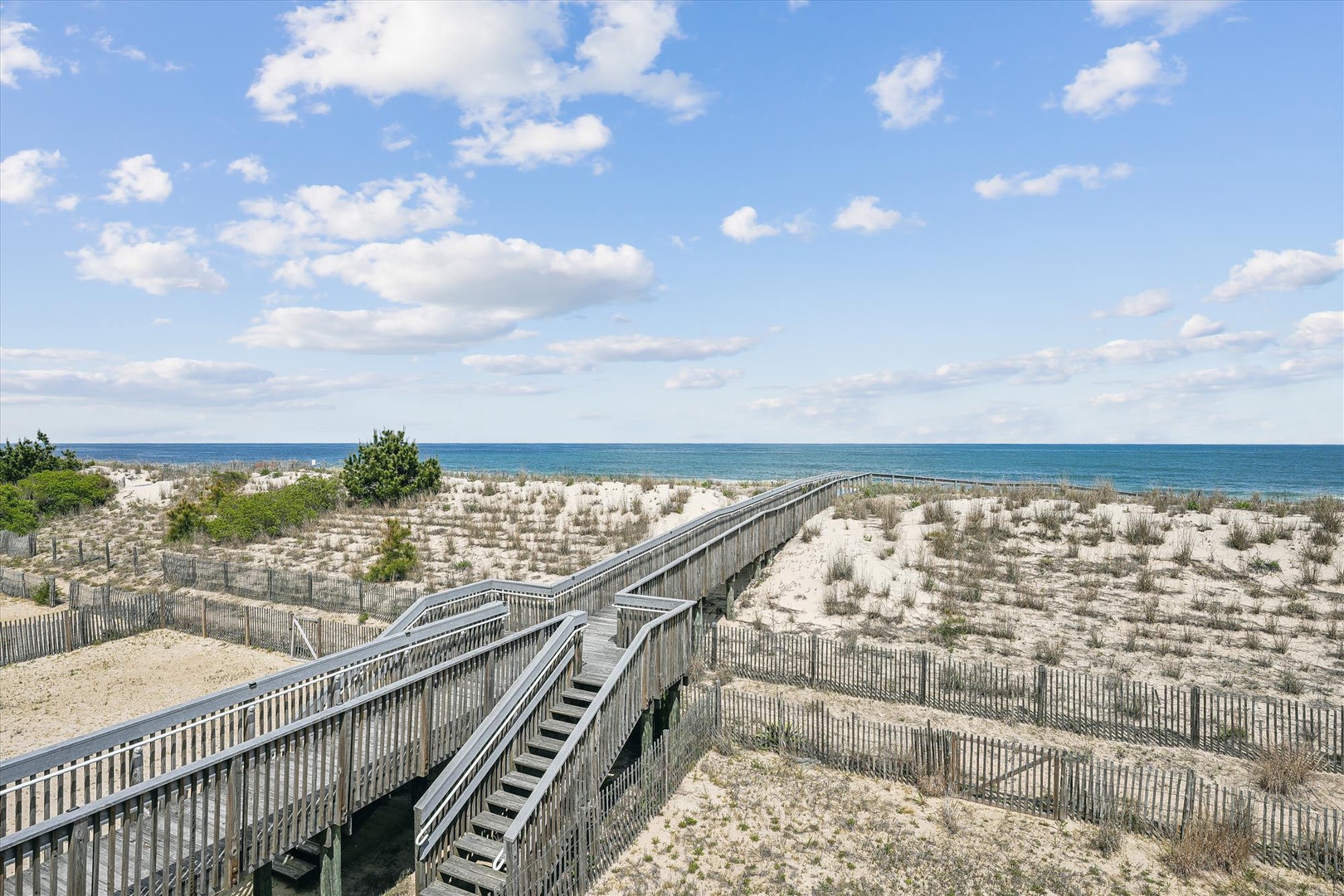 The property offers convenient beach access via a wooden boardwalk crossing natural dunes, leading to pristine sandy shores and sparkling ocean views.