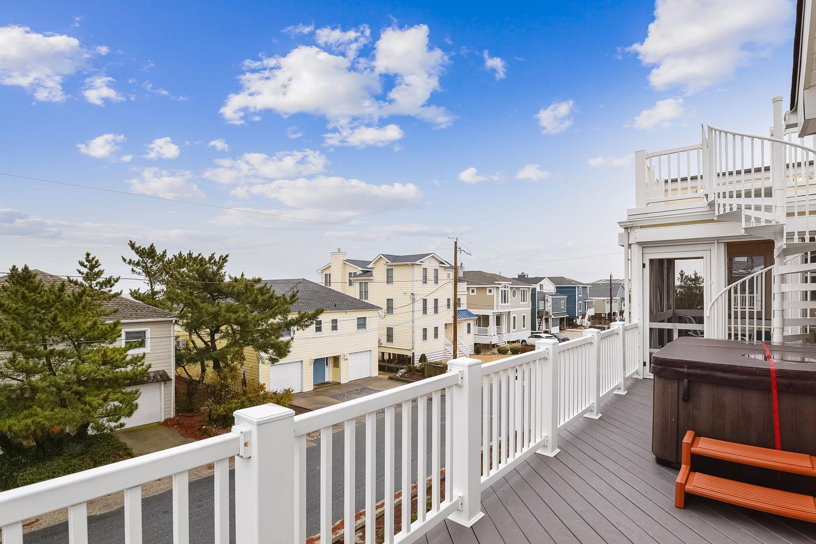 Step out onto your private deck and breathe in the fresh coastal air, where a hot tub awaits and the neighborhood stretches toward the horizon under endless blue skies.