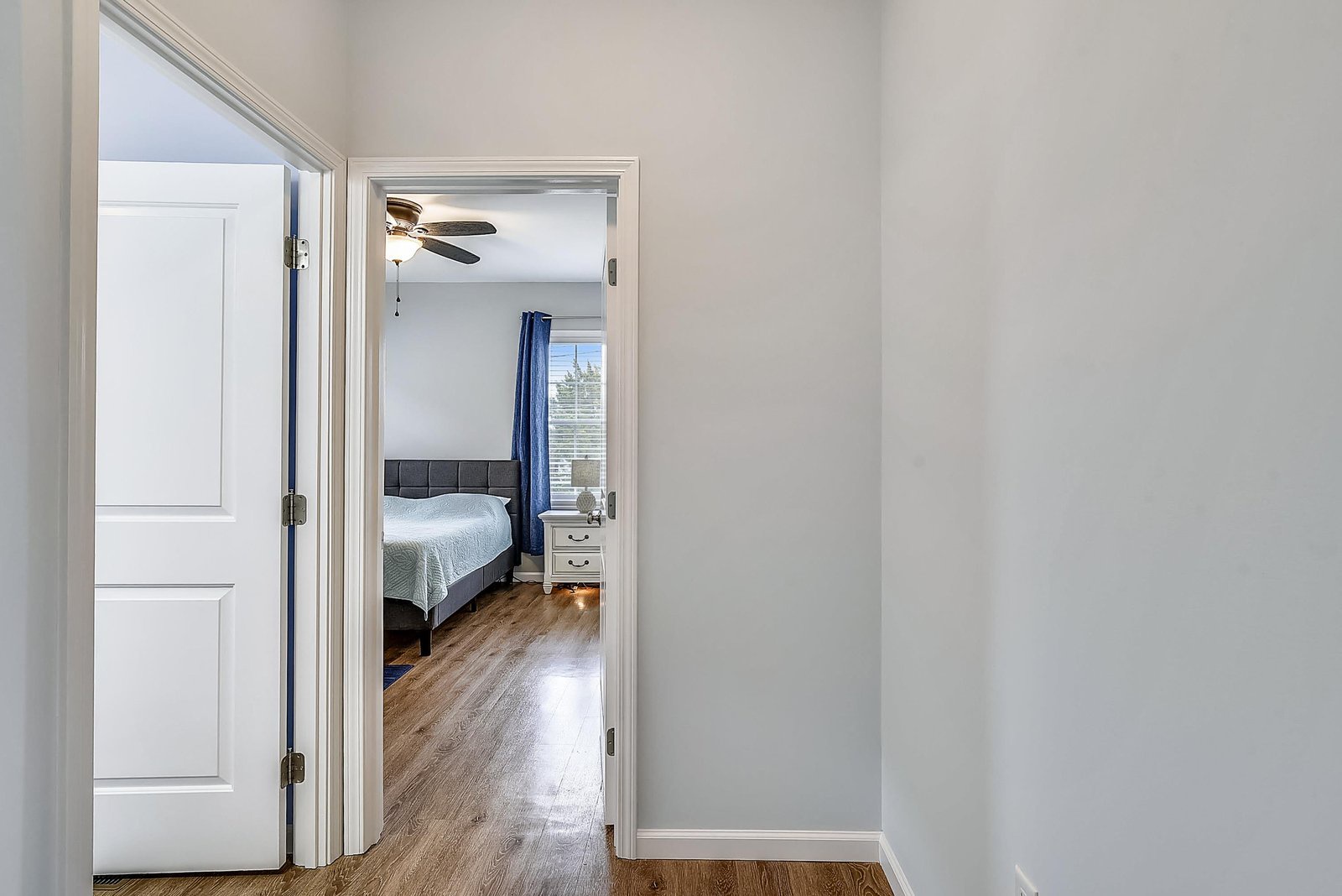Step through into your cozy bedroom retreat, where gleaming wood floors, a plush bed, and a ceiling fan await. A bright window invites natural light to greet your mornings.