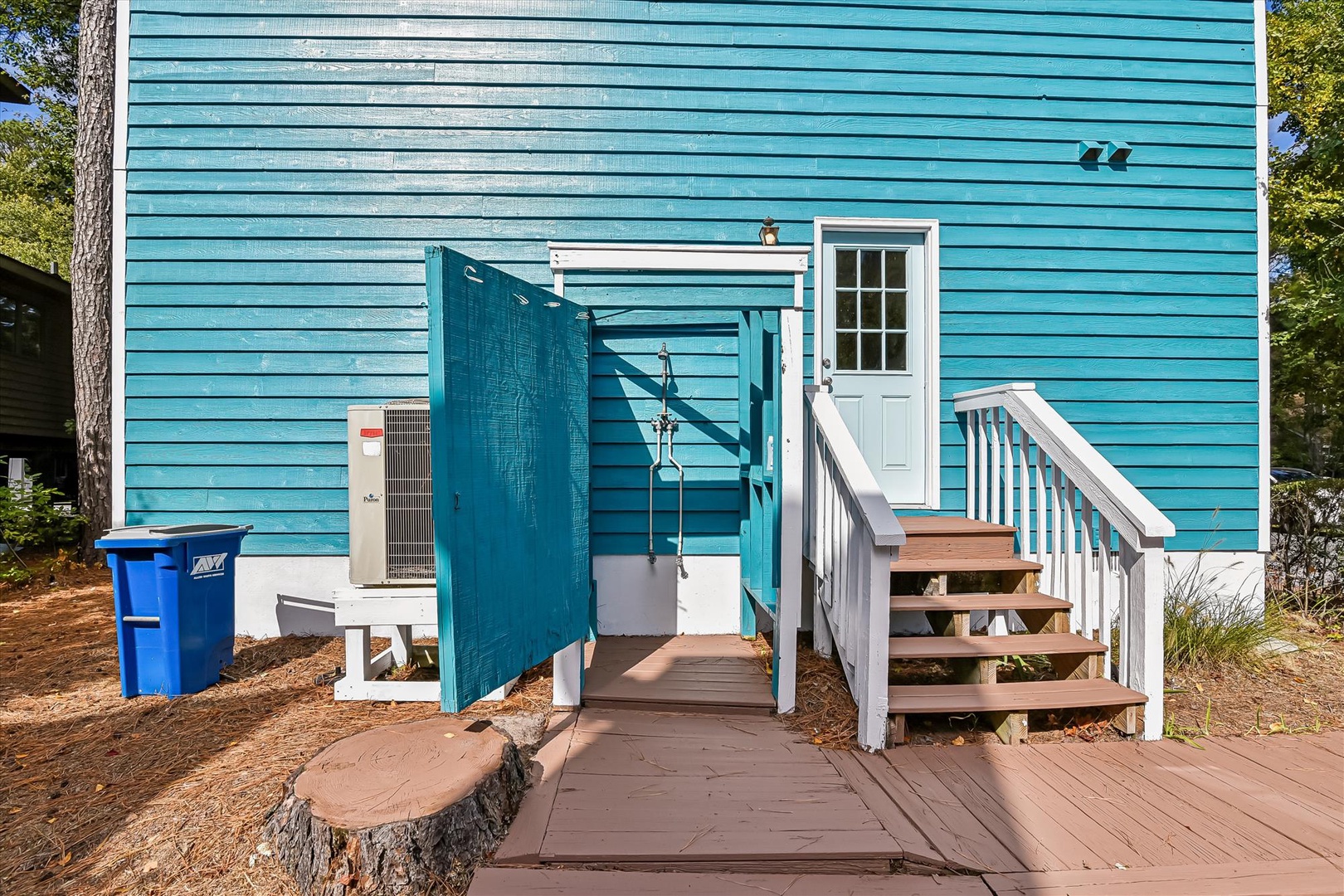 Charming turquoise cottage with welcoming entrance stairs and private outdoor shower for rinsing off after beach adventures.
