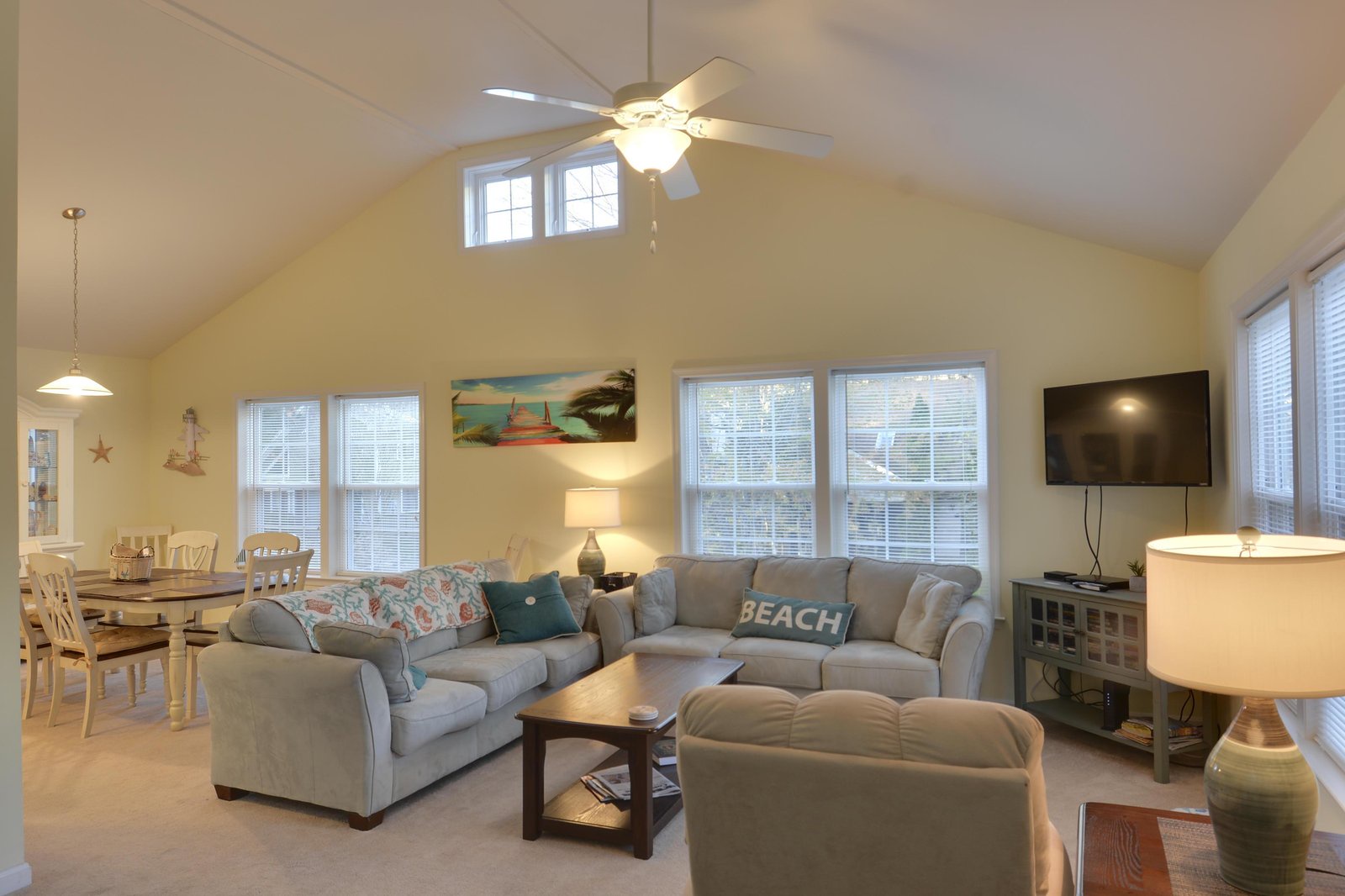 Sink into plush coastal comfort in this airy, light-filled living space where vaulted ceilings and beach-themed accents create your perfect retreat after a day of sun and surf.