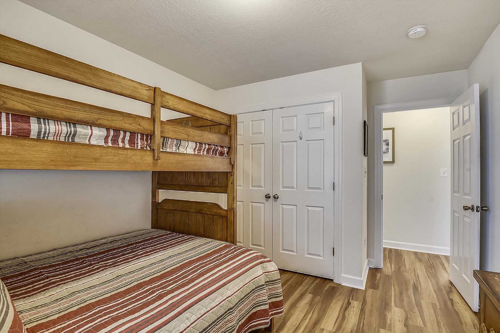 Your family's cozy retreat features a sturdy bunk bed with cheerful striped linens and warm wood tones. Ample closet space keeps everyone organized during your mountain escape.