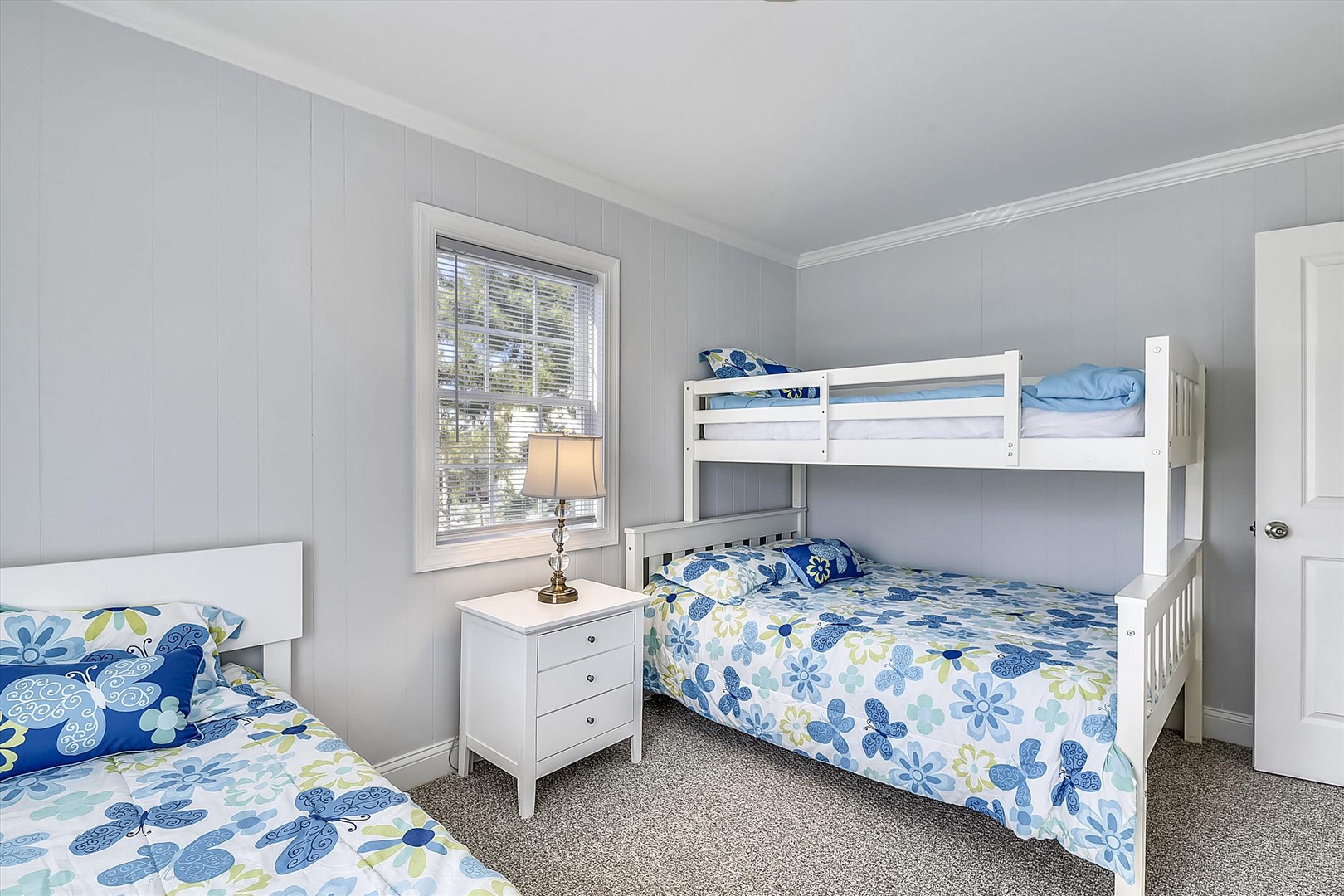 Bright bedroom with cheerful blue floral bedding, featuring a bunk bed and twin bed configuration perfect for groups or families traveling together.