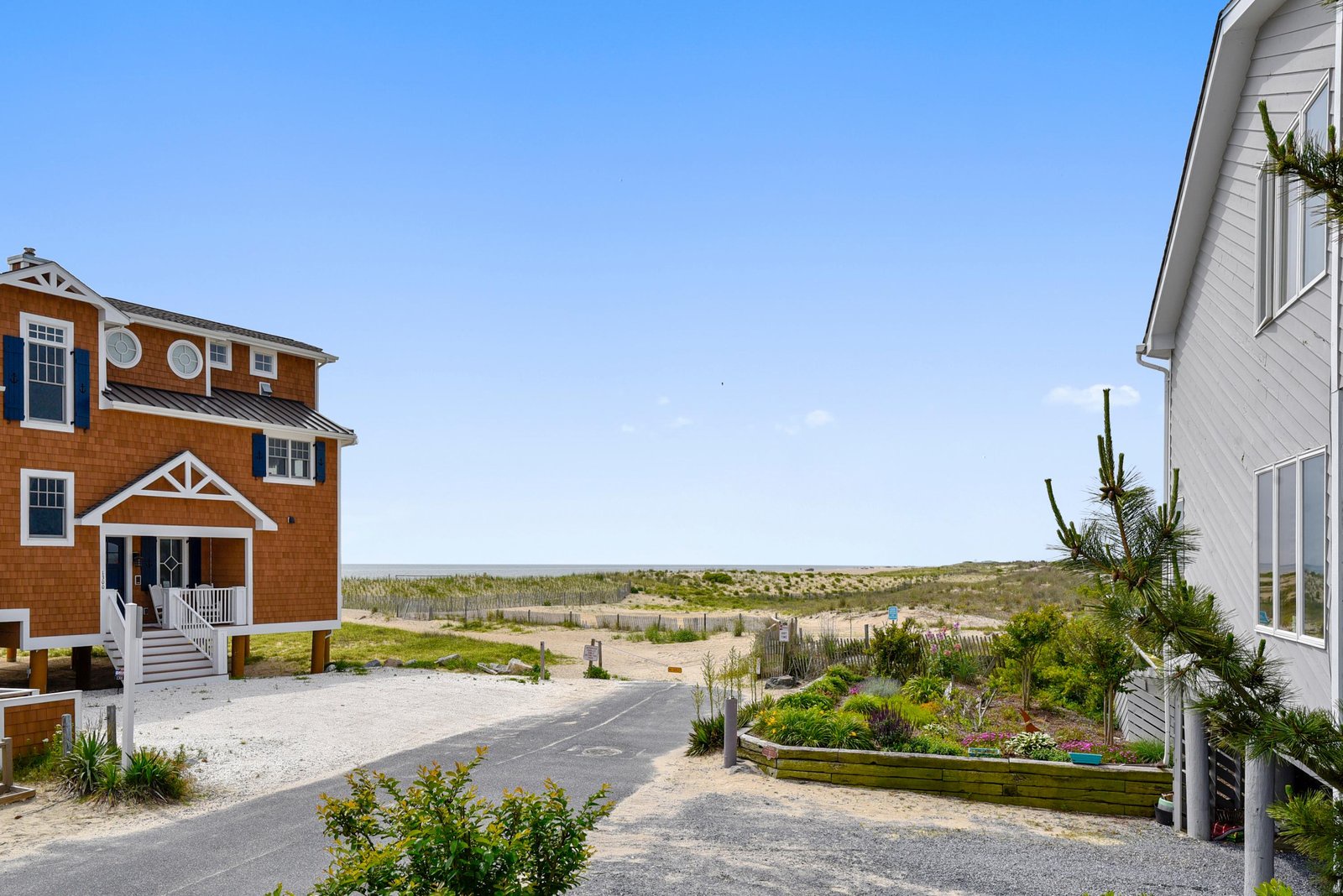 Charming beachside cottages framed by natural coastal dunes and sandy pathways, inviting you to step straight from your door into seaside tranquility.