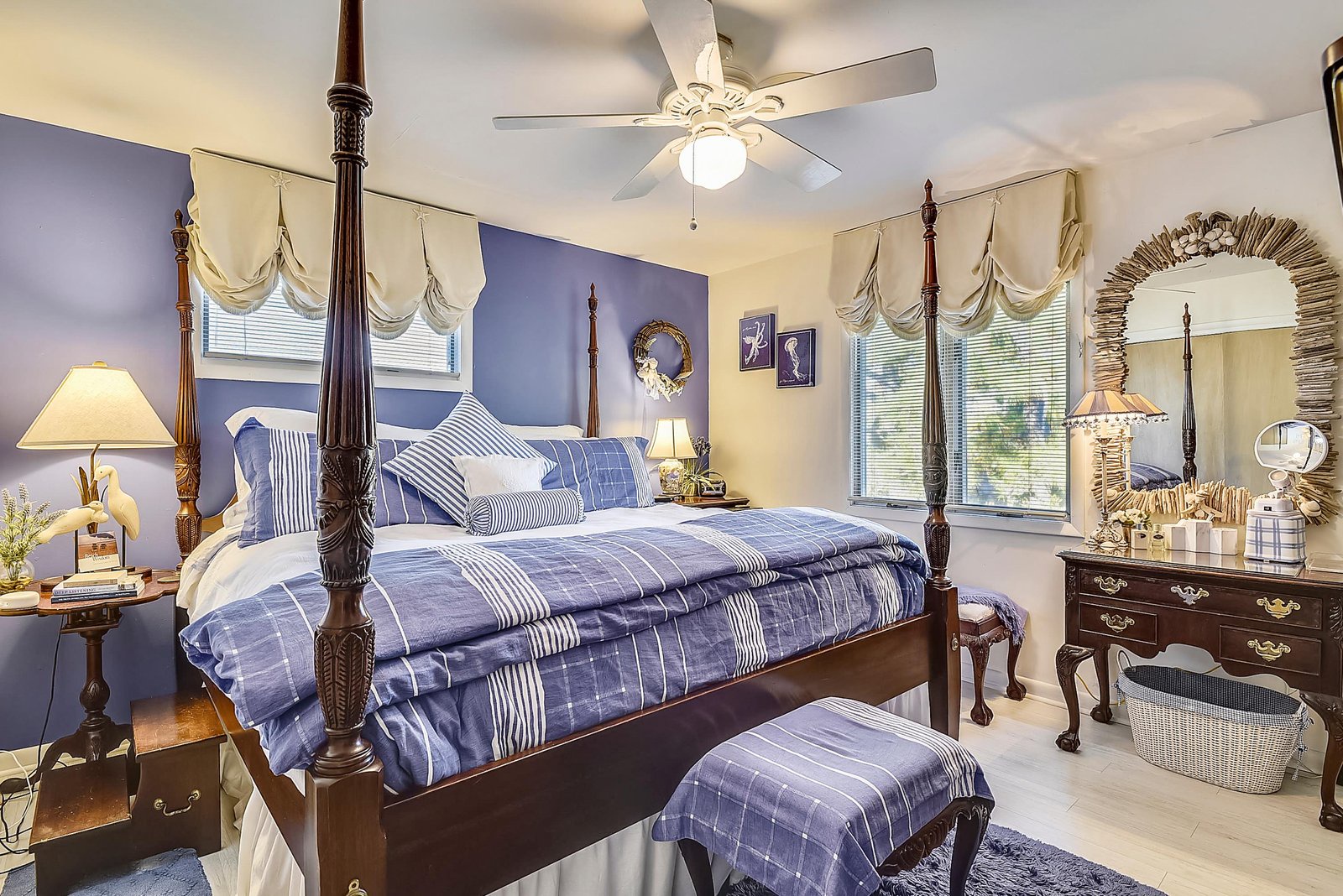Your elegant bedroom features a grand four-poster bed dressed in crisp linens, soft lighting from antique-style lamps, and charming windows that invite natural light. Unwind in this peaceful retreat with classic touches and comfortable furnishings.