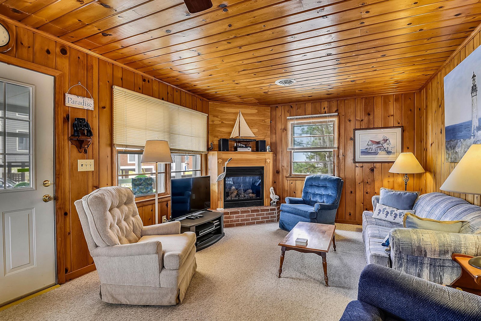 Settle into this cozy living room with knotty pine walls and a crackling fireplace—your perfect retreat after a day of mountain adventures.