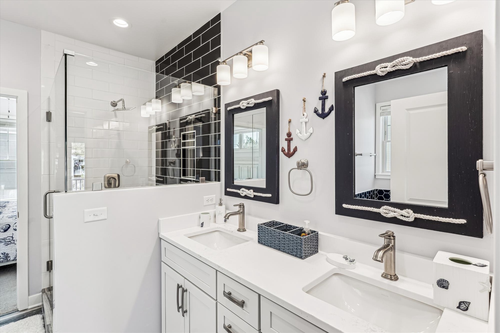 You'll love this coastal-inspired bathroom with dual sinks, a sleek glass-enclosed shower, and charming nautical décor—bright, clean, and ready for your morning routine.